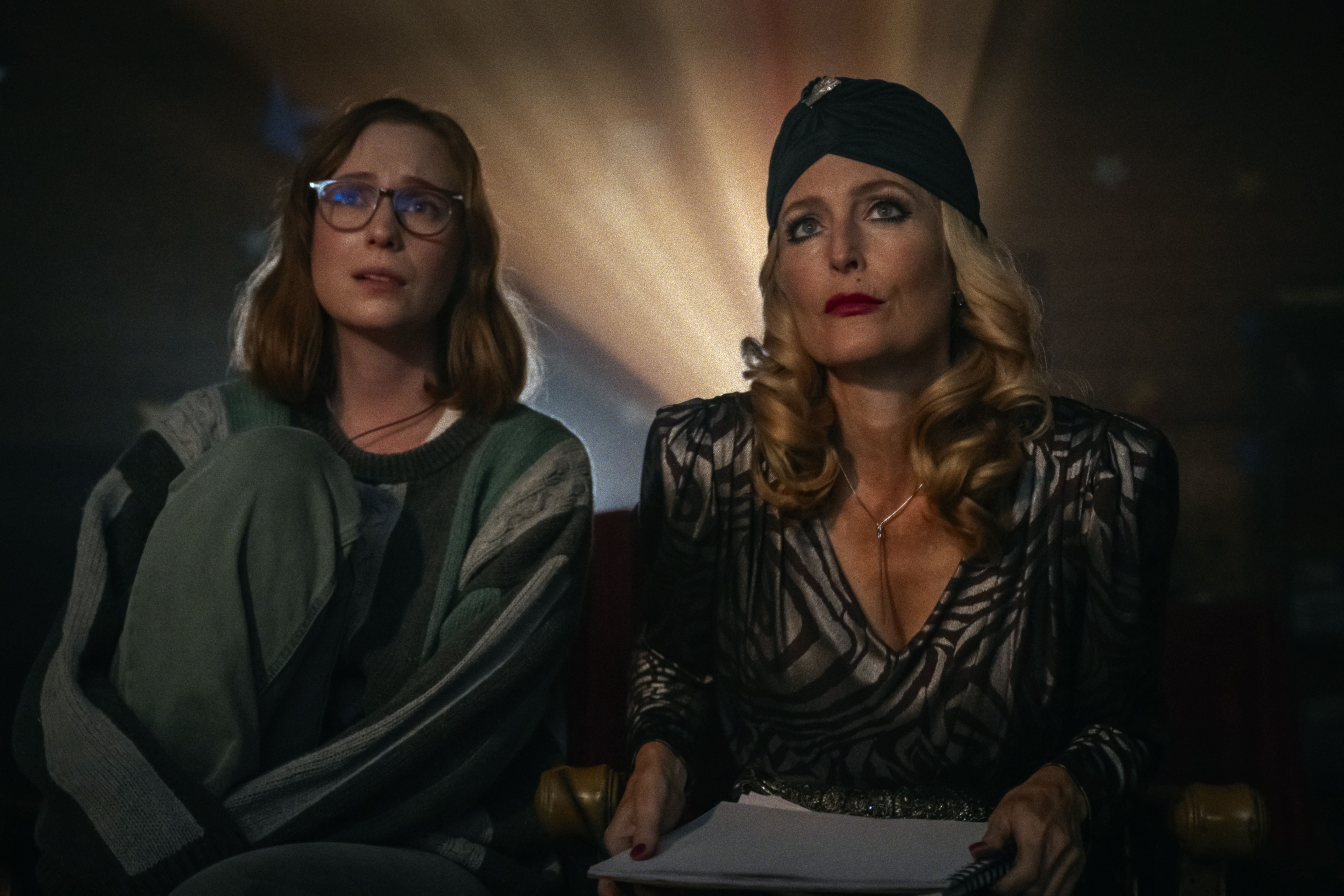 Hannah Einbinder as Kris and Gillian Anderson as Billy sit side by side, with Billy wearing a black head covering.