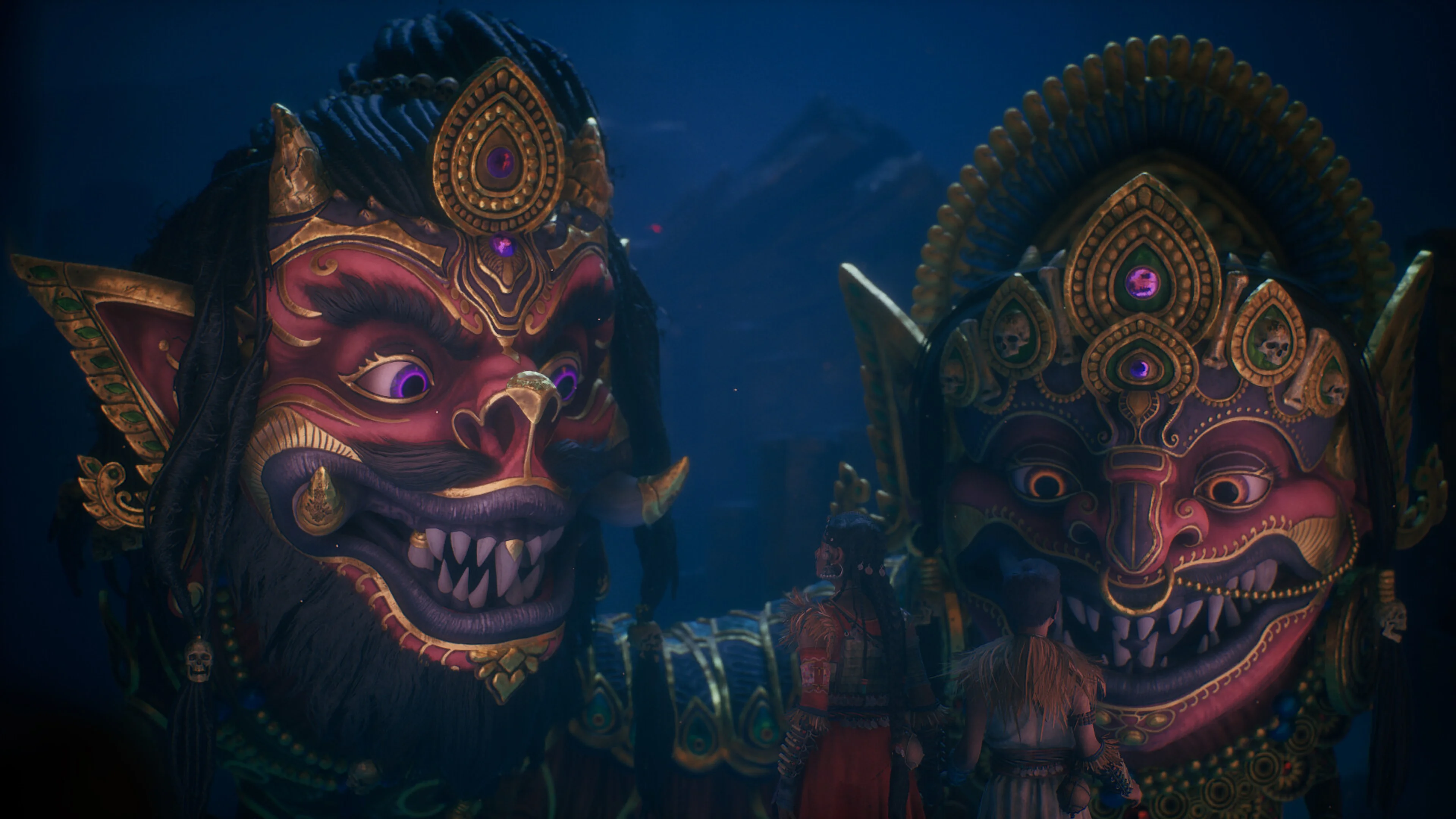 Raji and Darsh stand before two enormous, brightly ornamented faces in Raji: Kaliyuga.