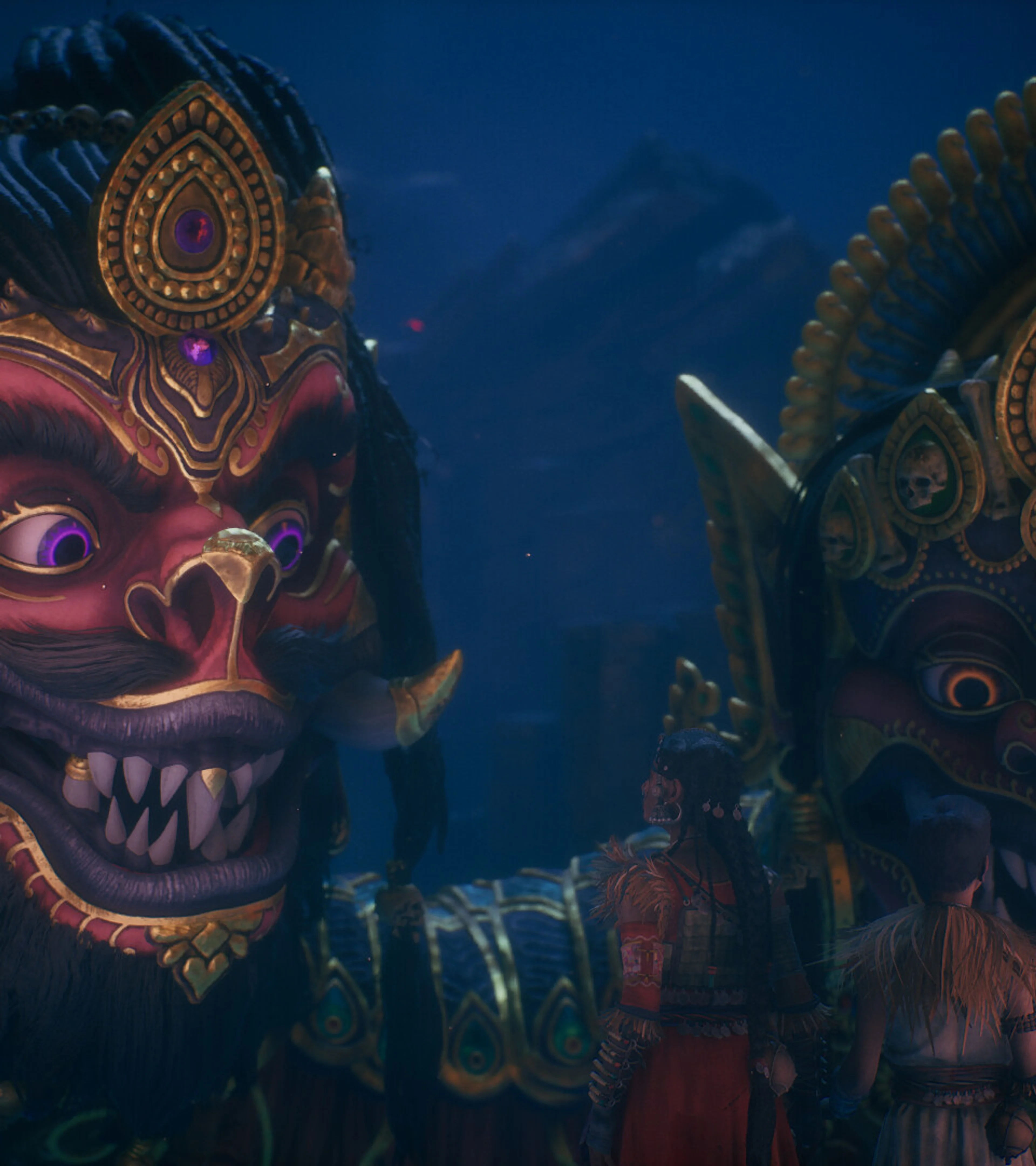 Raji and Darsh stand before two enormous, brightly ornamented faces in Raji: Kaliyuga.