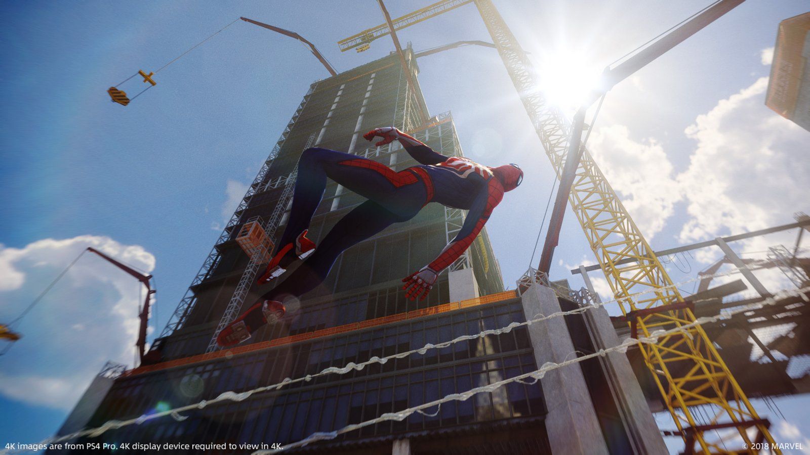 Spider-Man swings past a construction site in daylight.