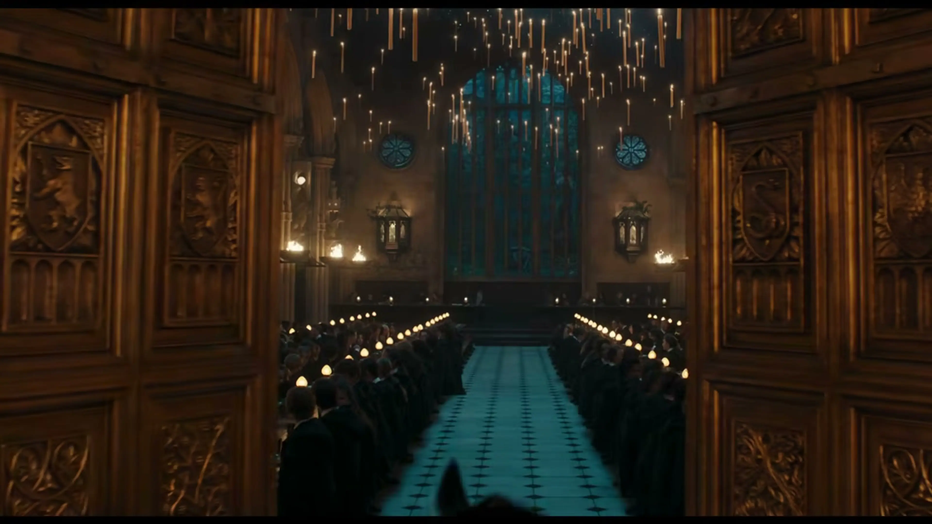 The candlelit Hogwarts Great Hall appears beyond open carved wooden doors.