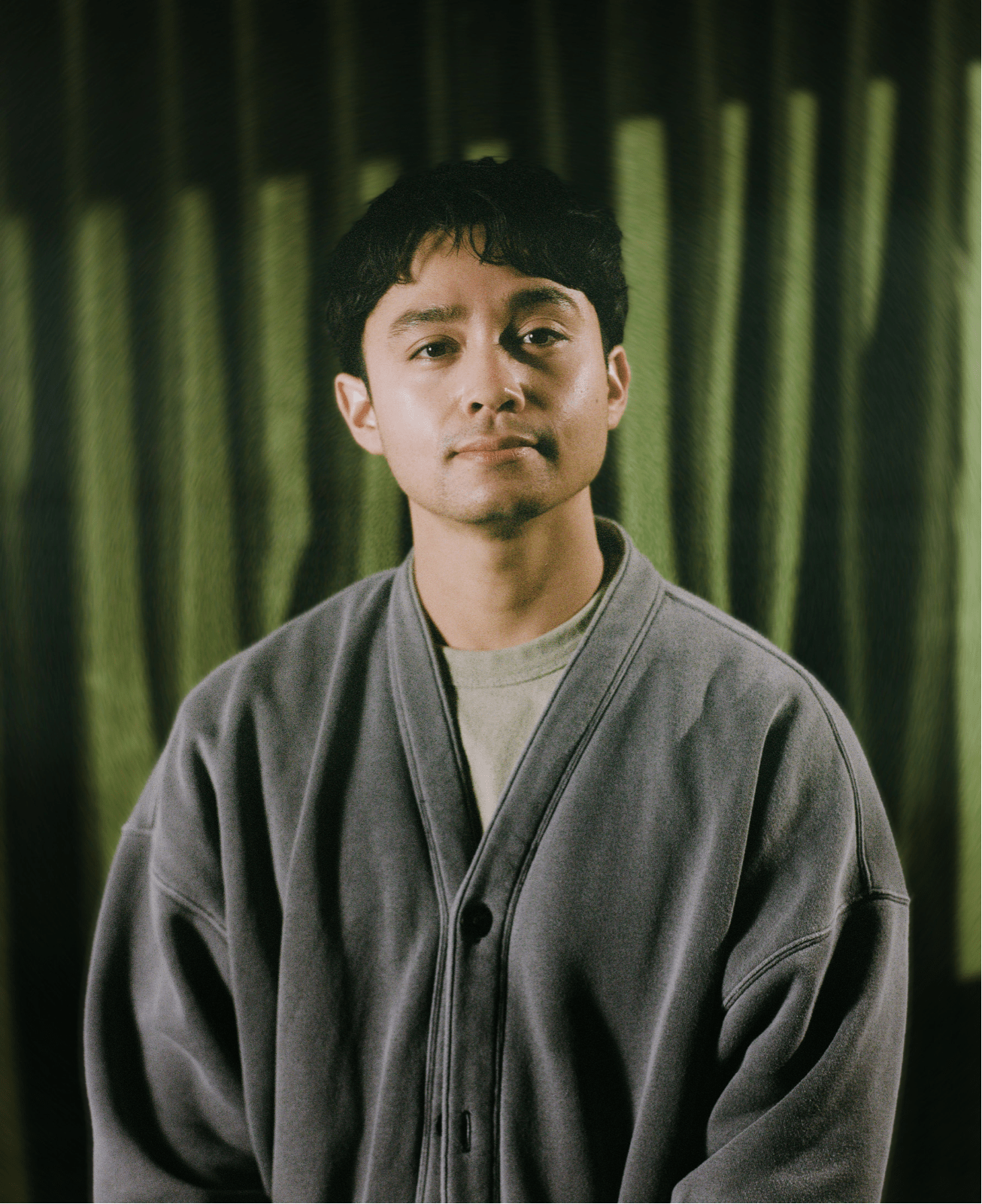 Jordan Mendoza wearing a gray cardigan in an official publicity portrait.