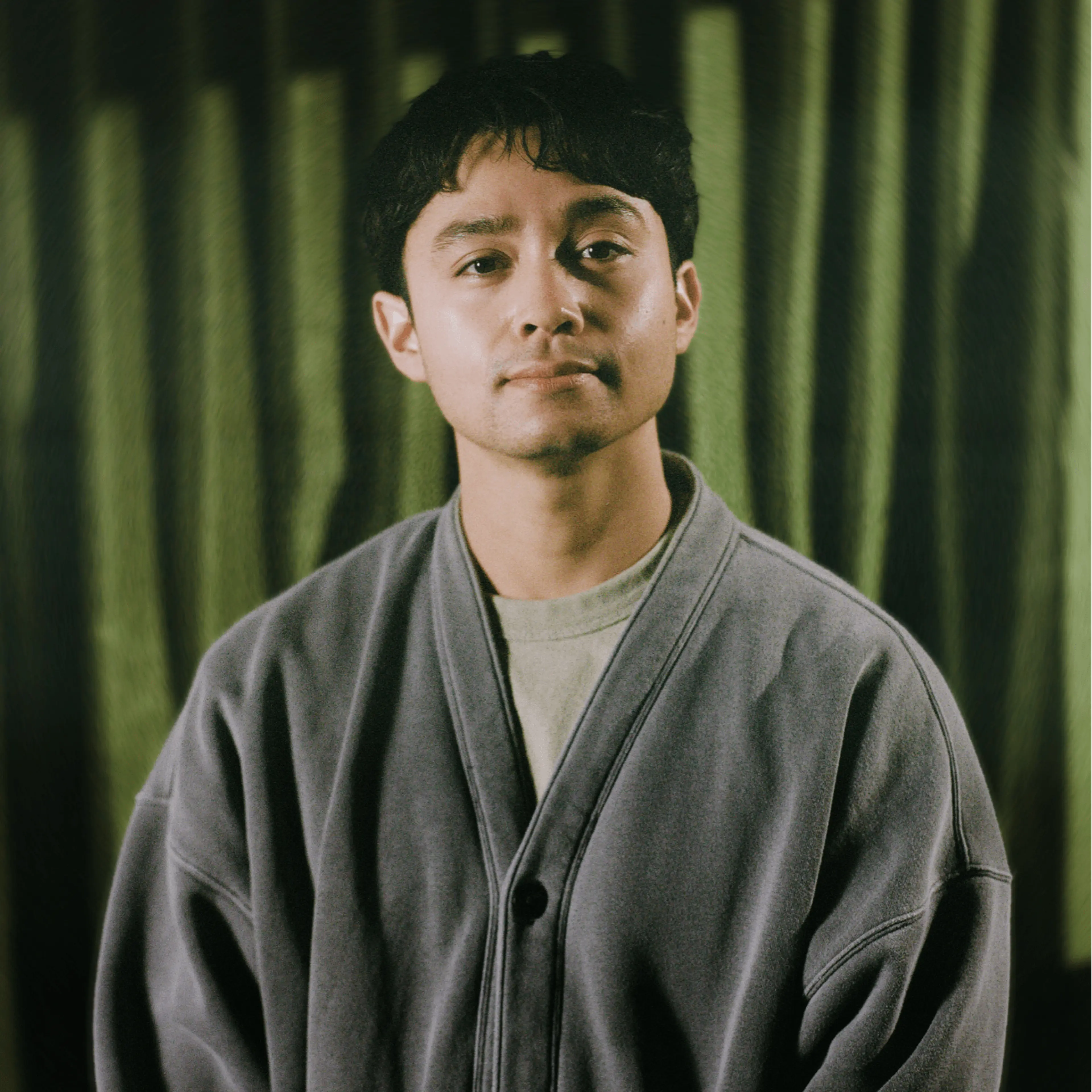 Jordan Mendoza wearing a gray cardigan in an official publicity portrait.