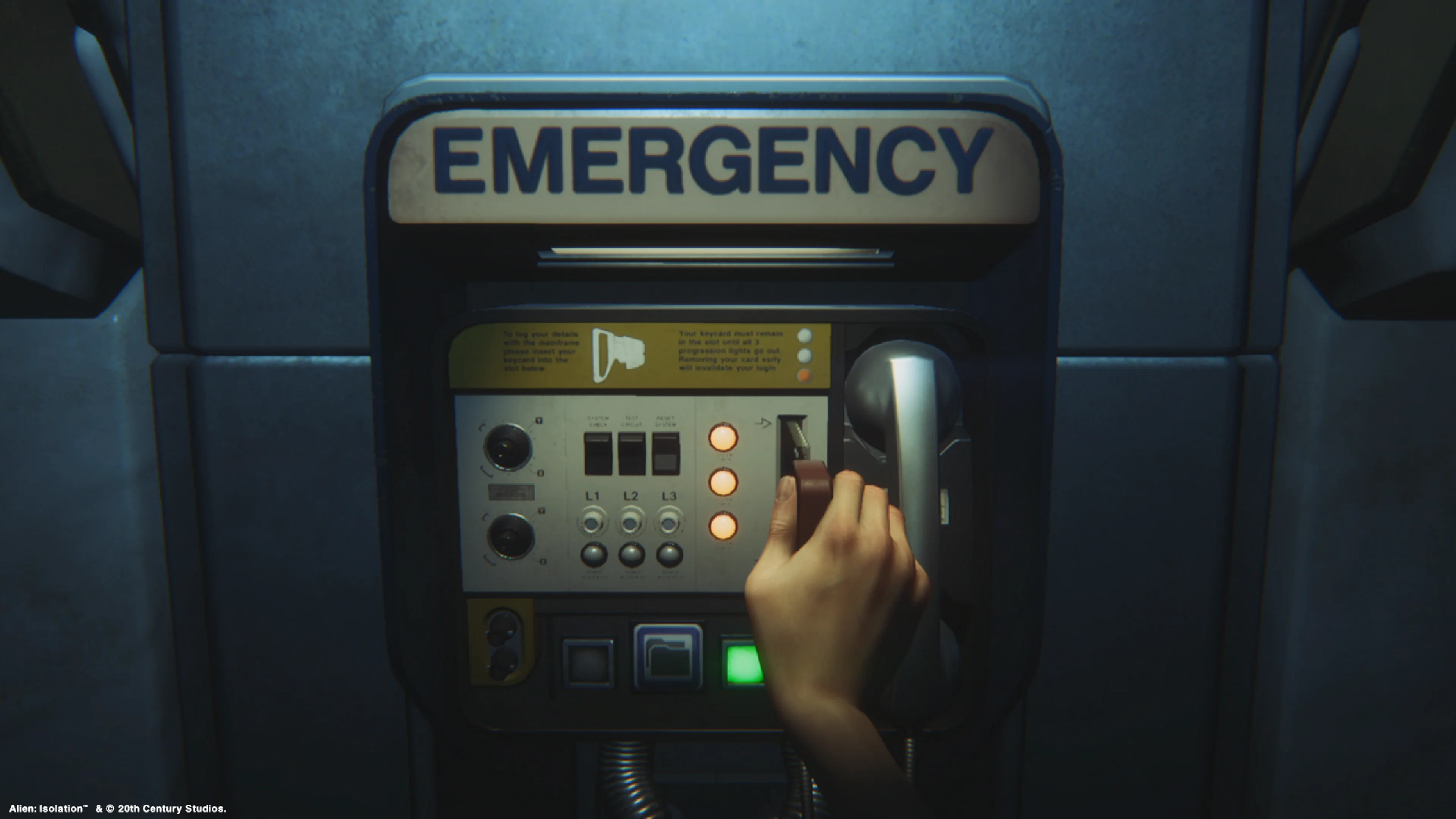 Official Alien: Isolation gameplay still of the wall-mounted Emergency save station, with a large EMERGENCY sign, handset on the right, three indicator lights and a green button.