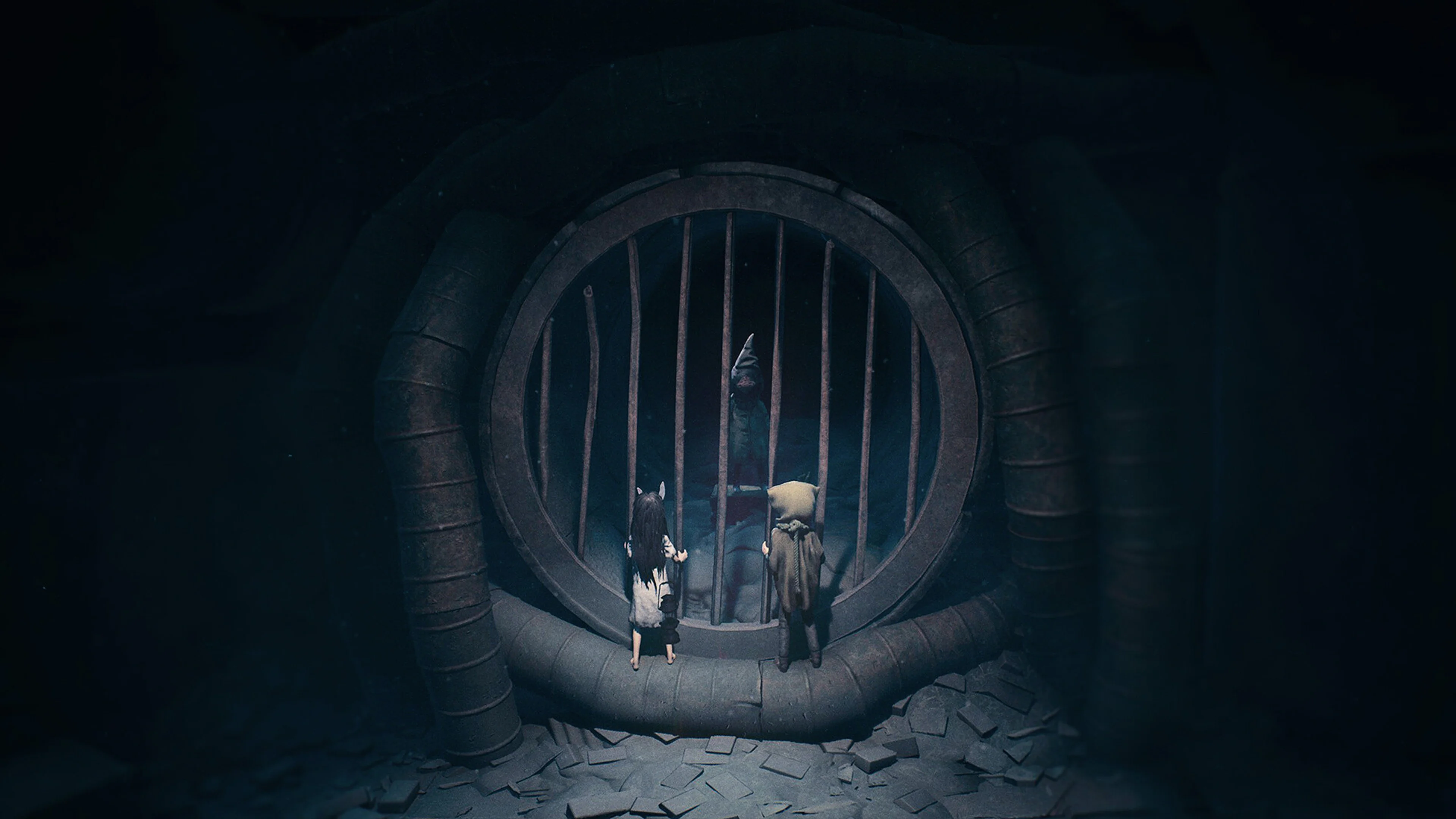 The two siblings in REANIMAL stand before a large barred opening with a figure waiting on the other side.