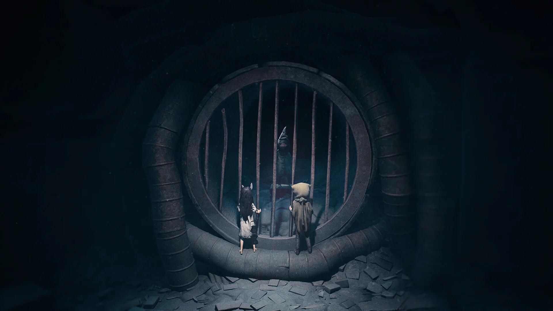 The two siblings in REANIMAL stand before a large barred opening with a figure waiting on the other side.
