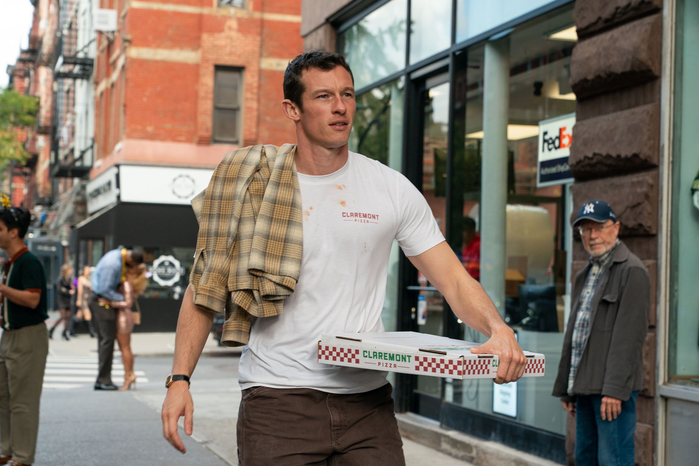 Callum Turner as Owen carries pizza boxes along a New York sidewalk in One Night Only.