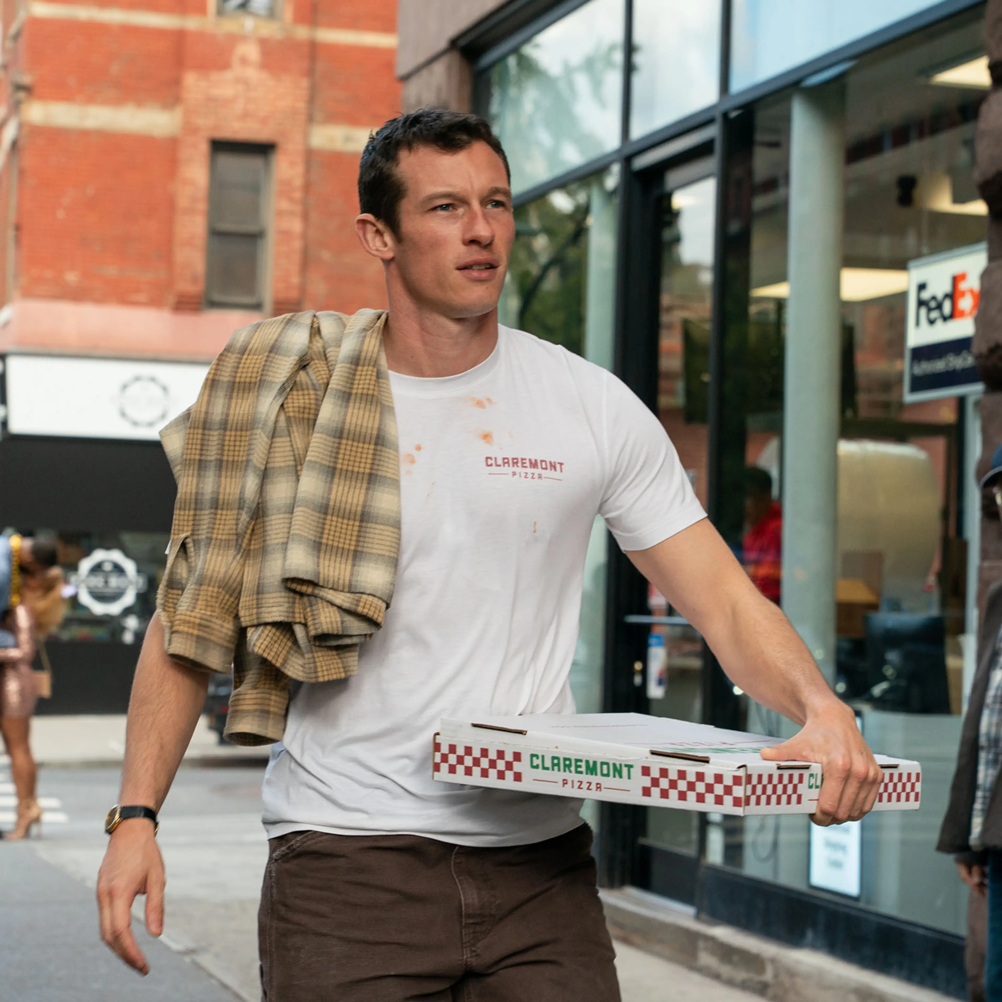Callum Turner as Owen carries pizza boxes along a New York sidewalk in One Night Only.