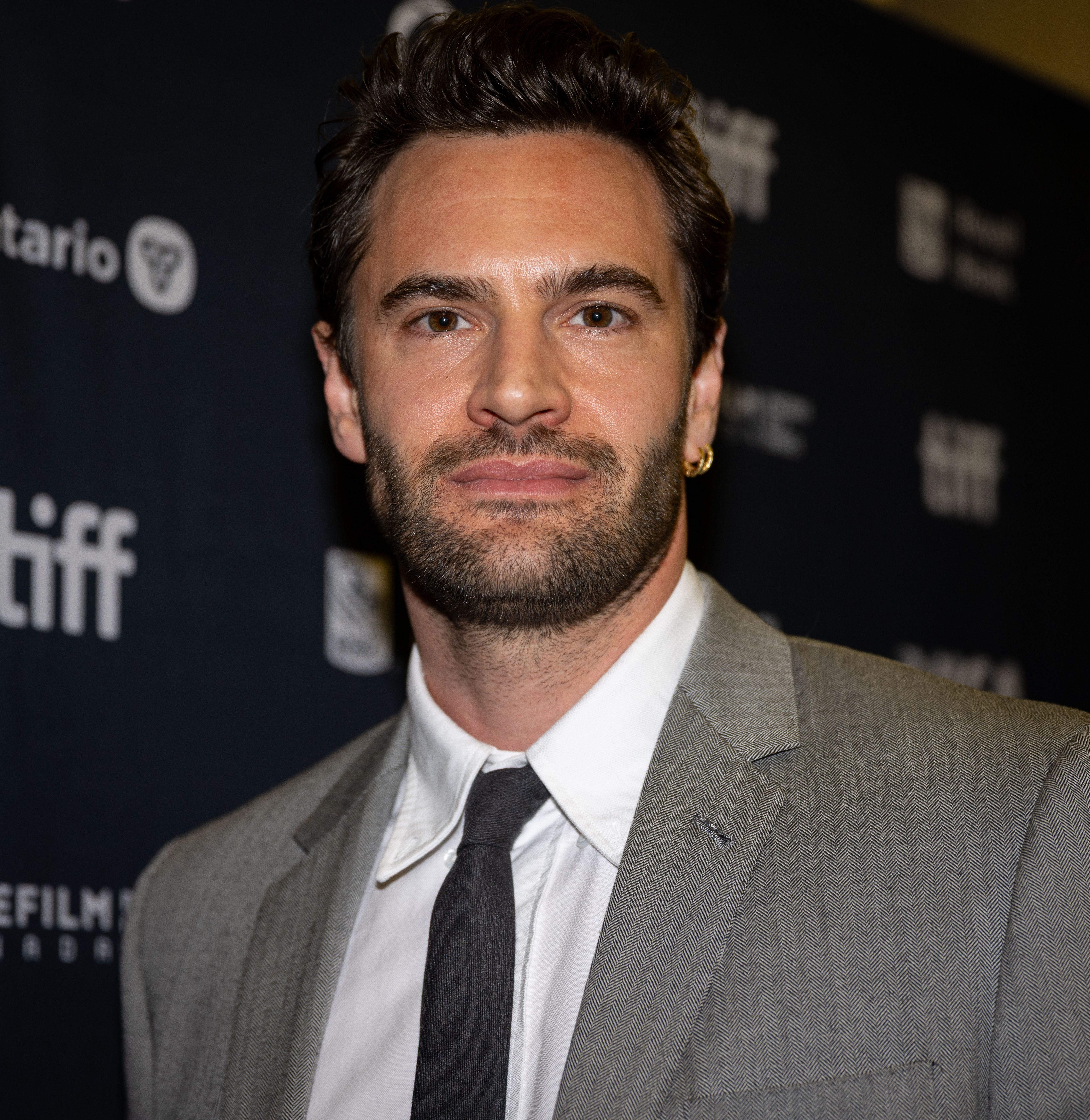Tom Bateman in a gray suit at the 2025 Toronto International Film Festival.
