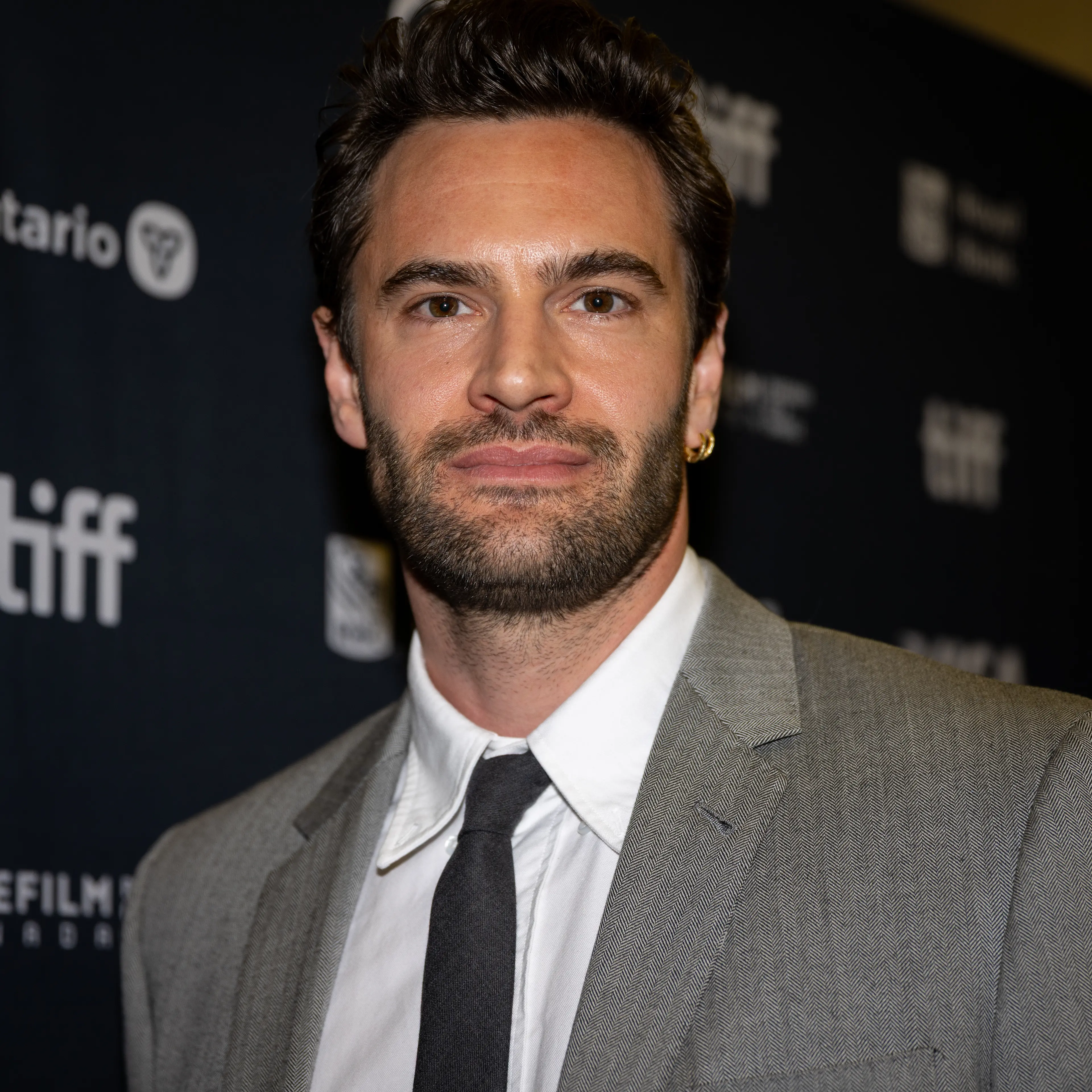 Tom Bateman in a gray suit at the 2025 Toronto International Film Festival.