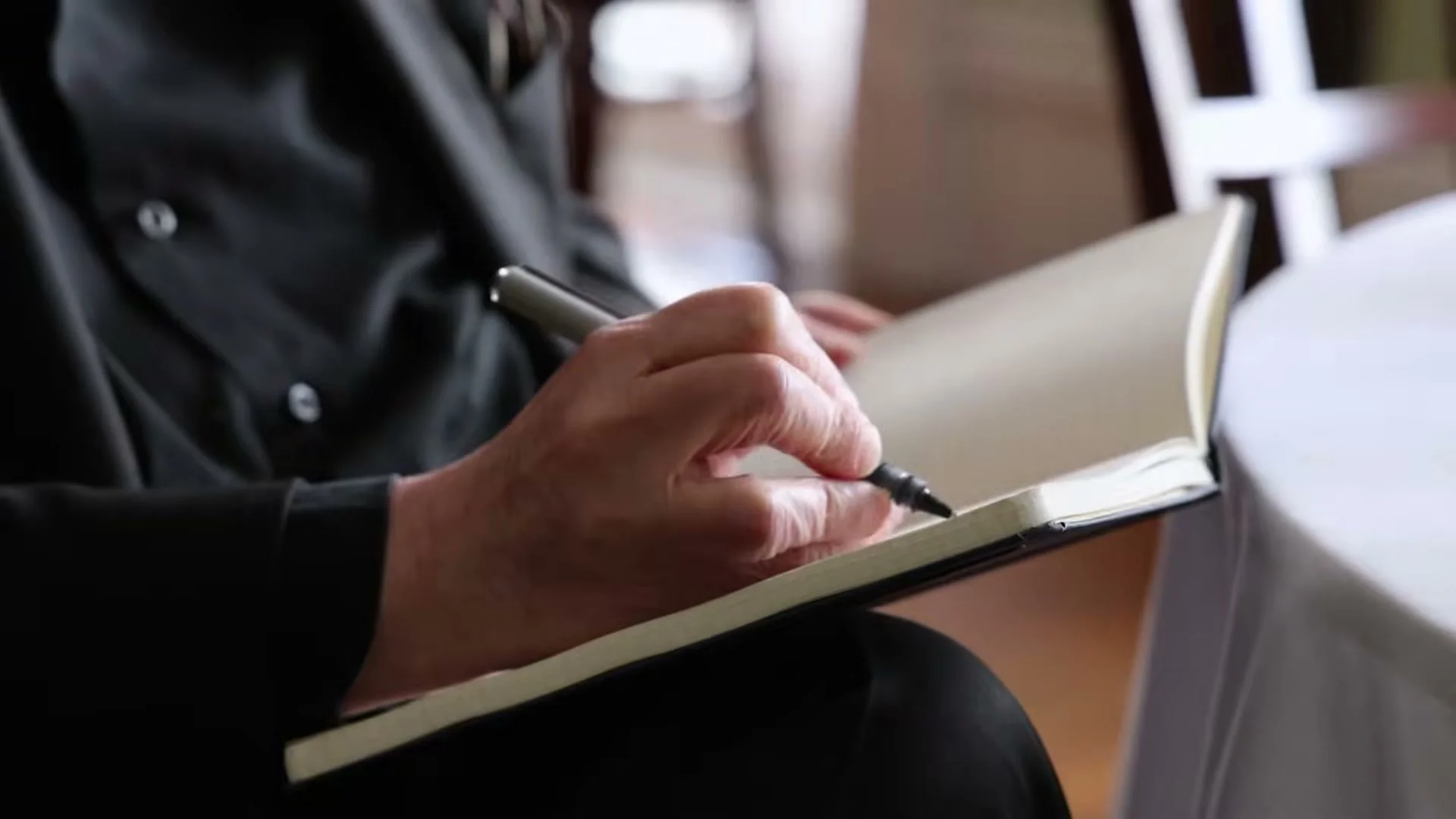 A hand writes in a notebook during the Knife documentary trailer.