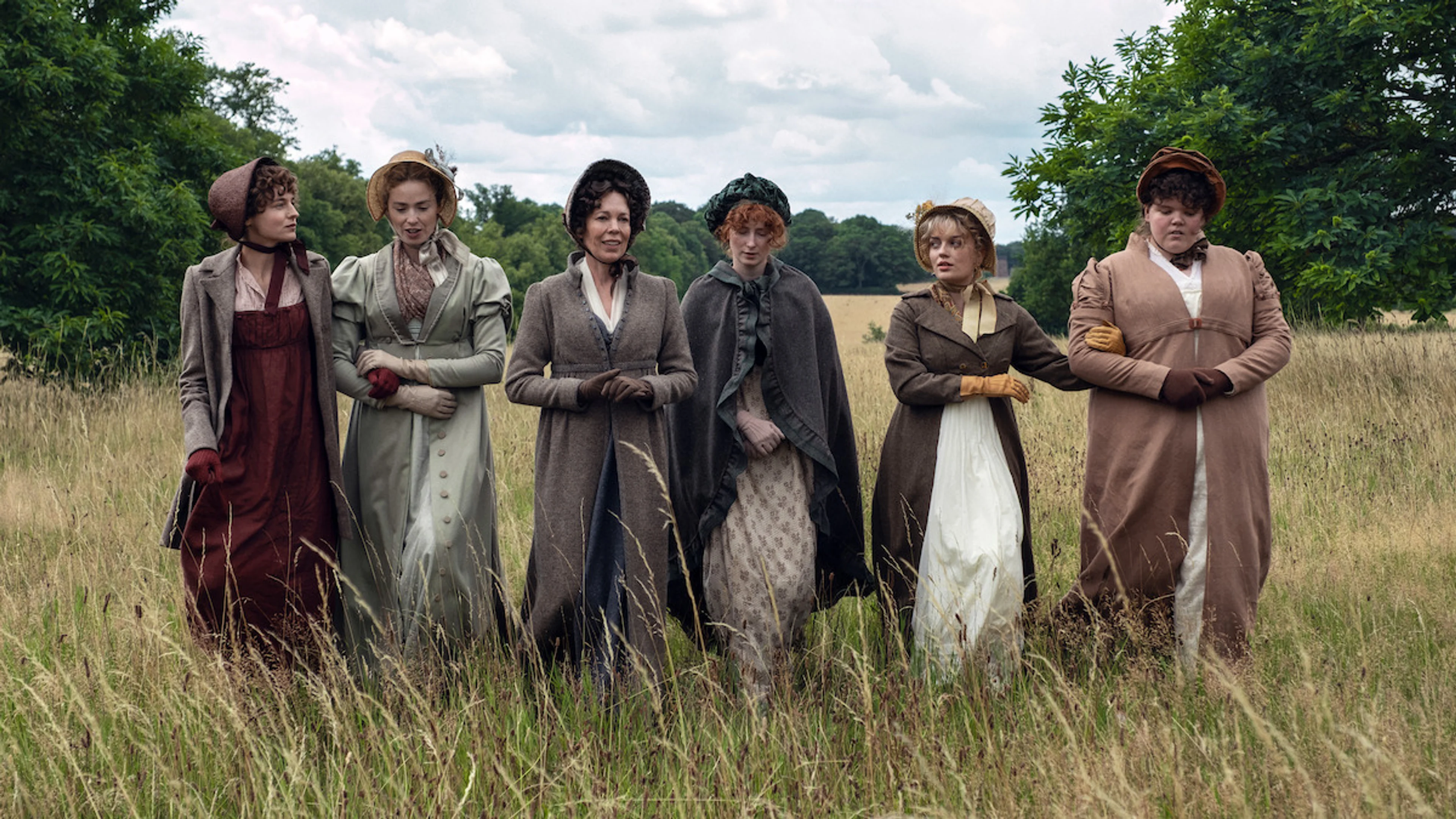 The six Bennet sisters and their mother stand together in a field in an official Pride and Prejudice first-look photo.
