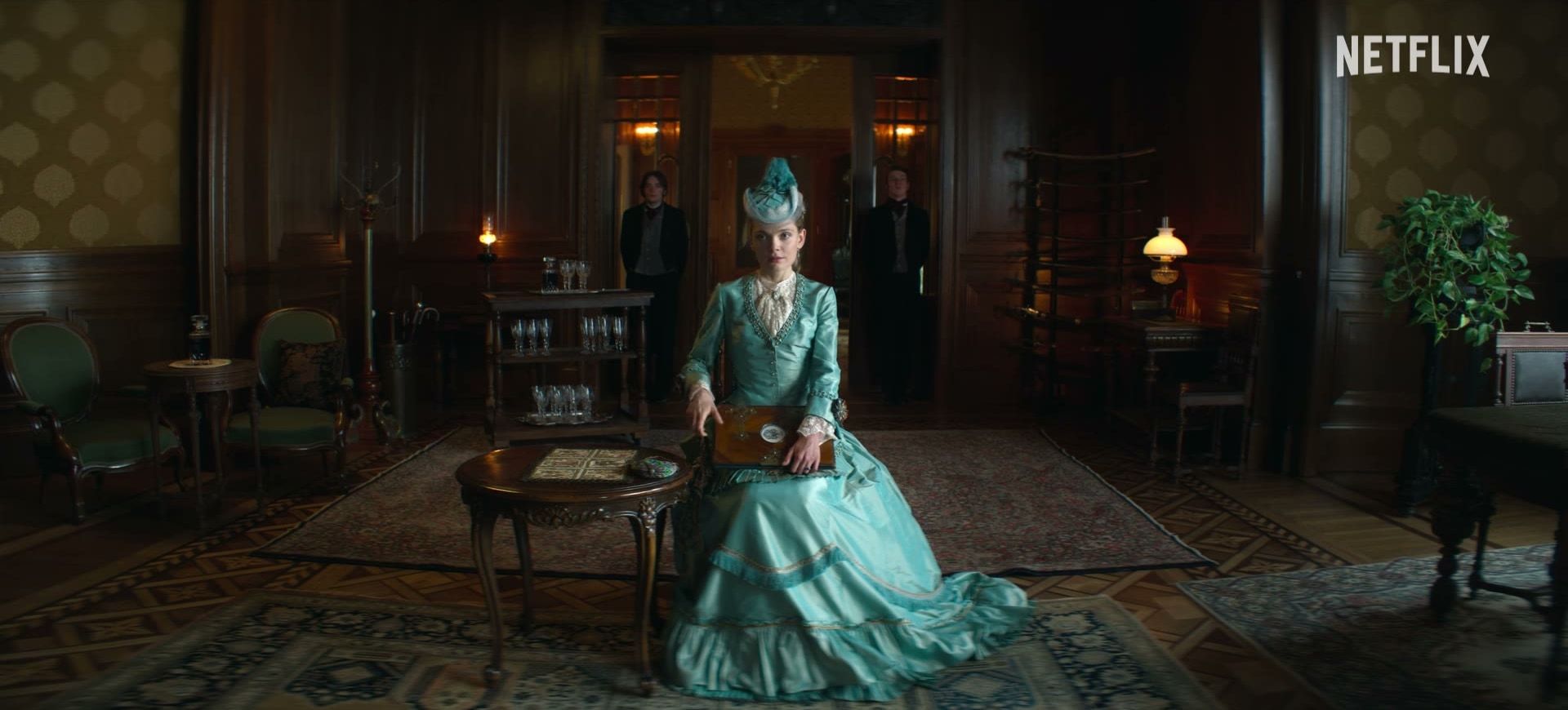 Izabela sits in a blue gown in an elegant Warsaw drawing room.