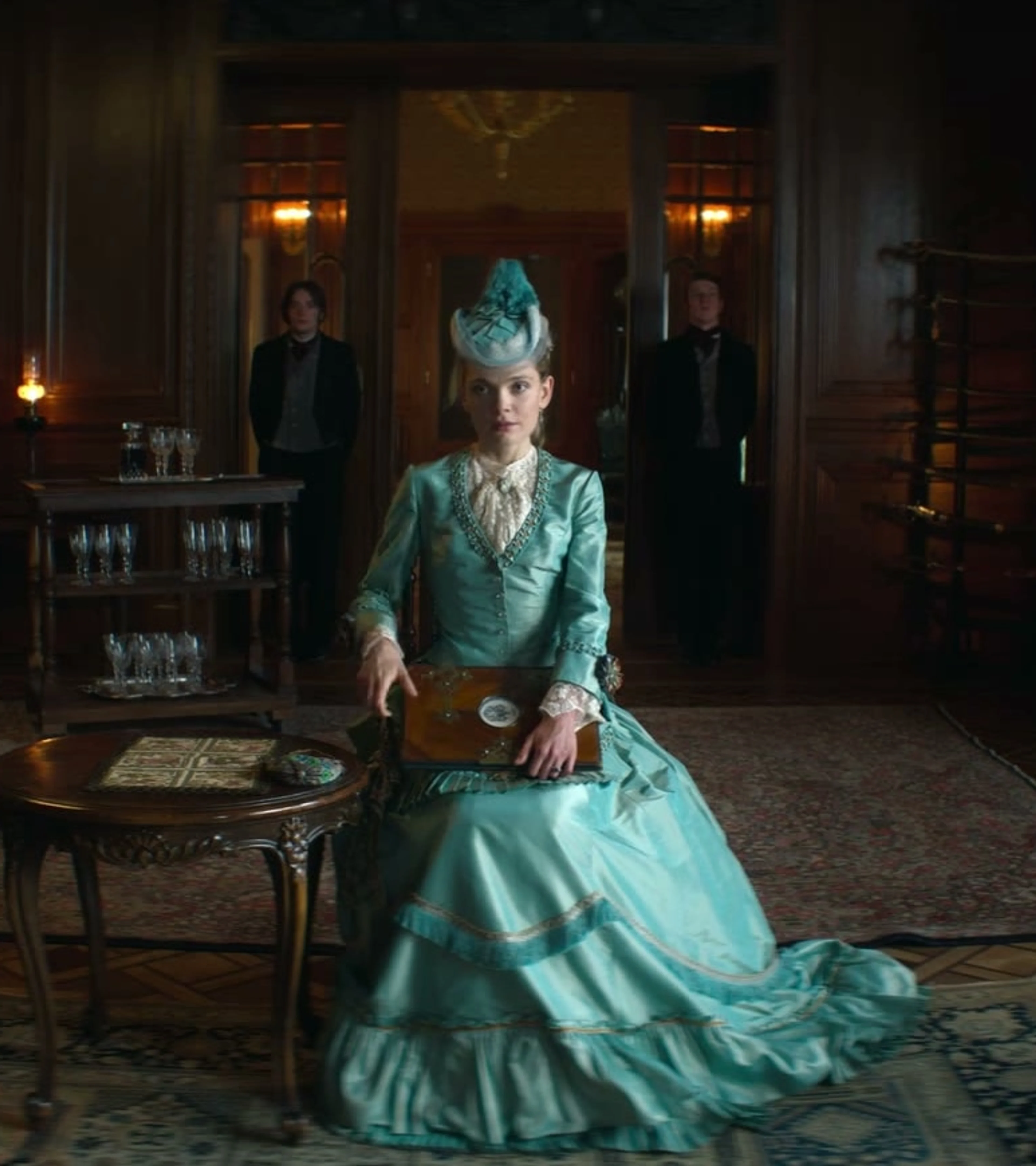 Izabela sits in a blue gown in an elegant Warsaw drawing room.