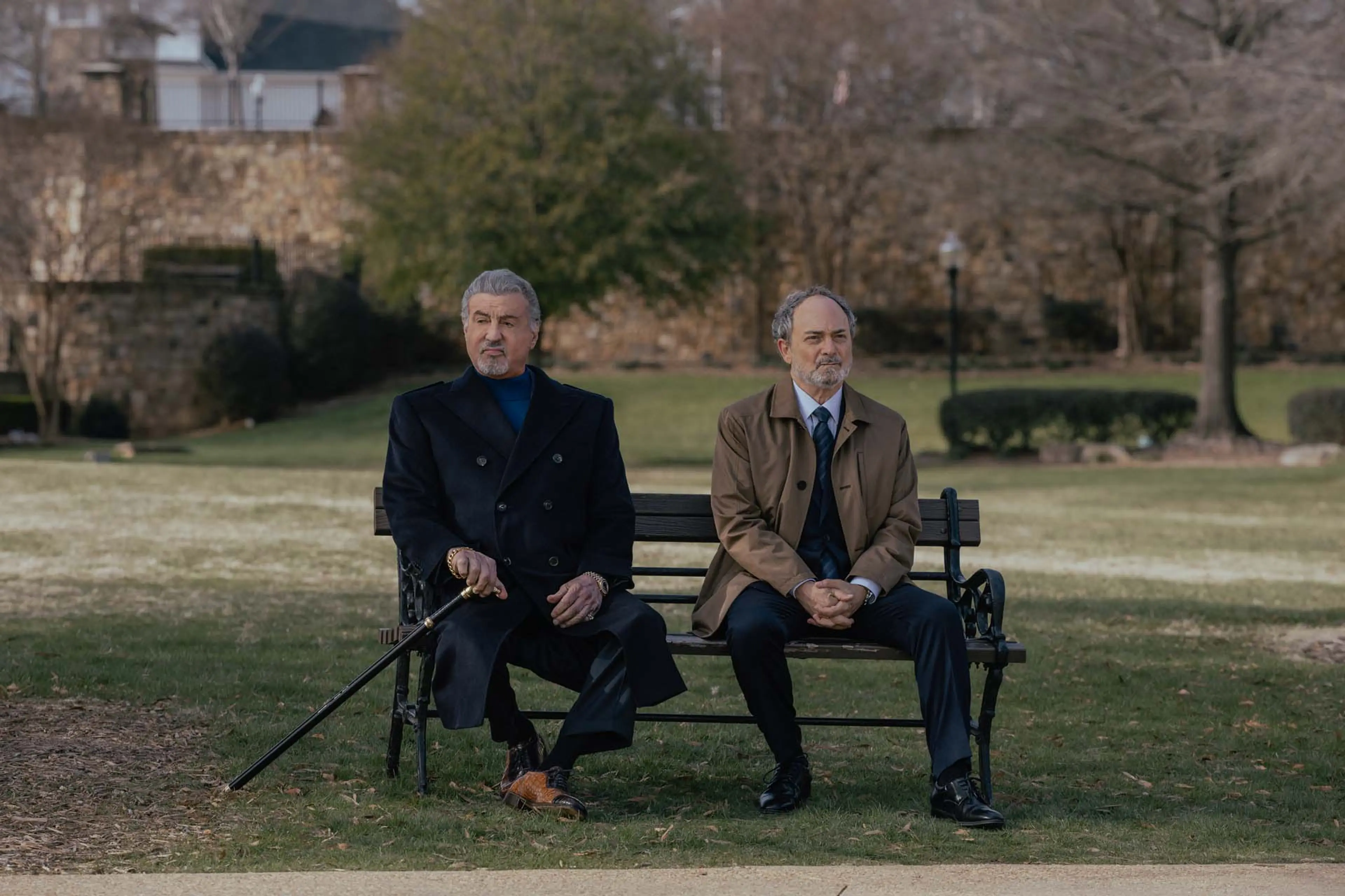 Sylvester Stallone as Dwight Manfredi and Kevin Pollak as Special Agent Musso sit on a park bench.