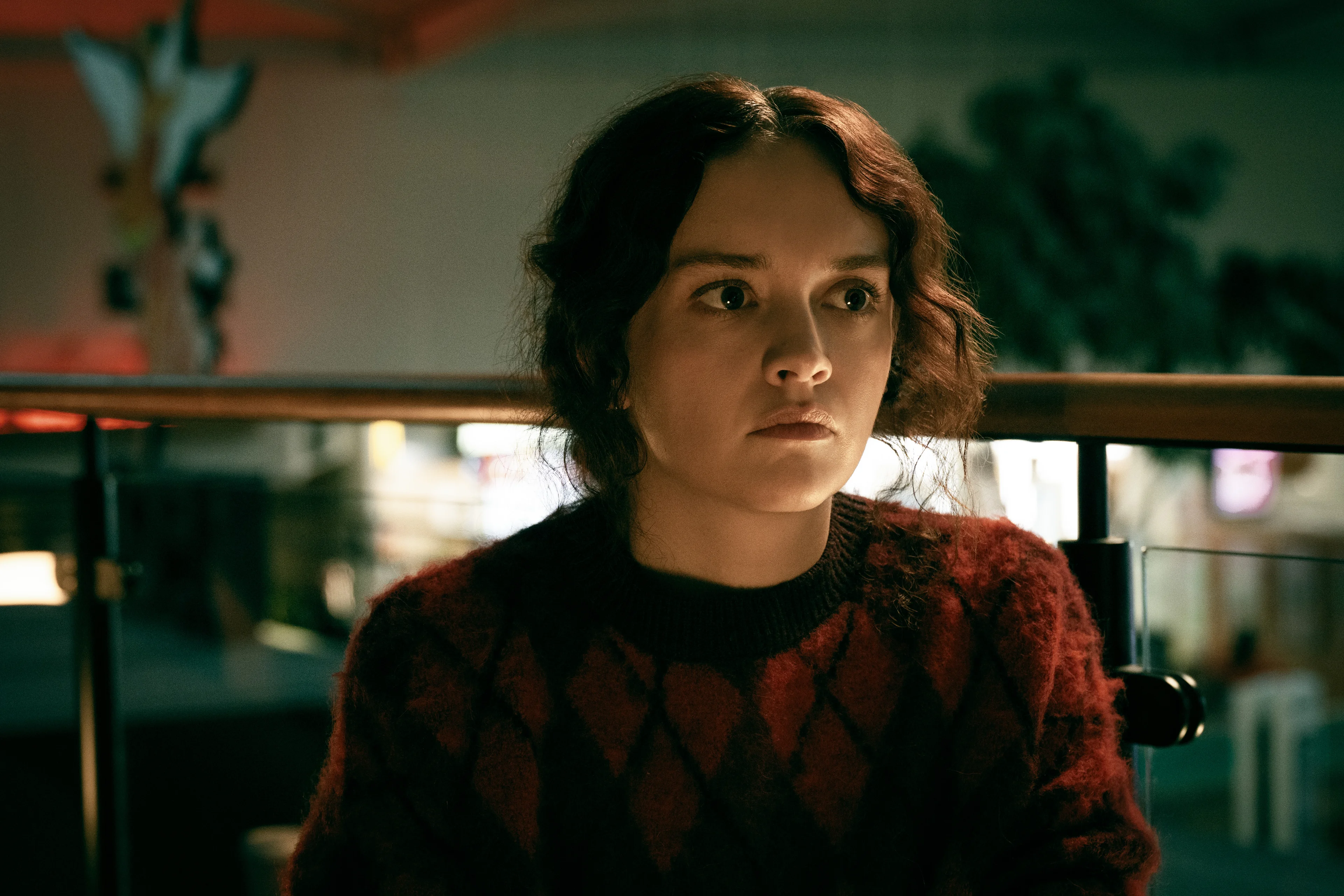 Olivia Cooke as Sid Baker looks through a glass shelf in Slow Horses Season 6.