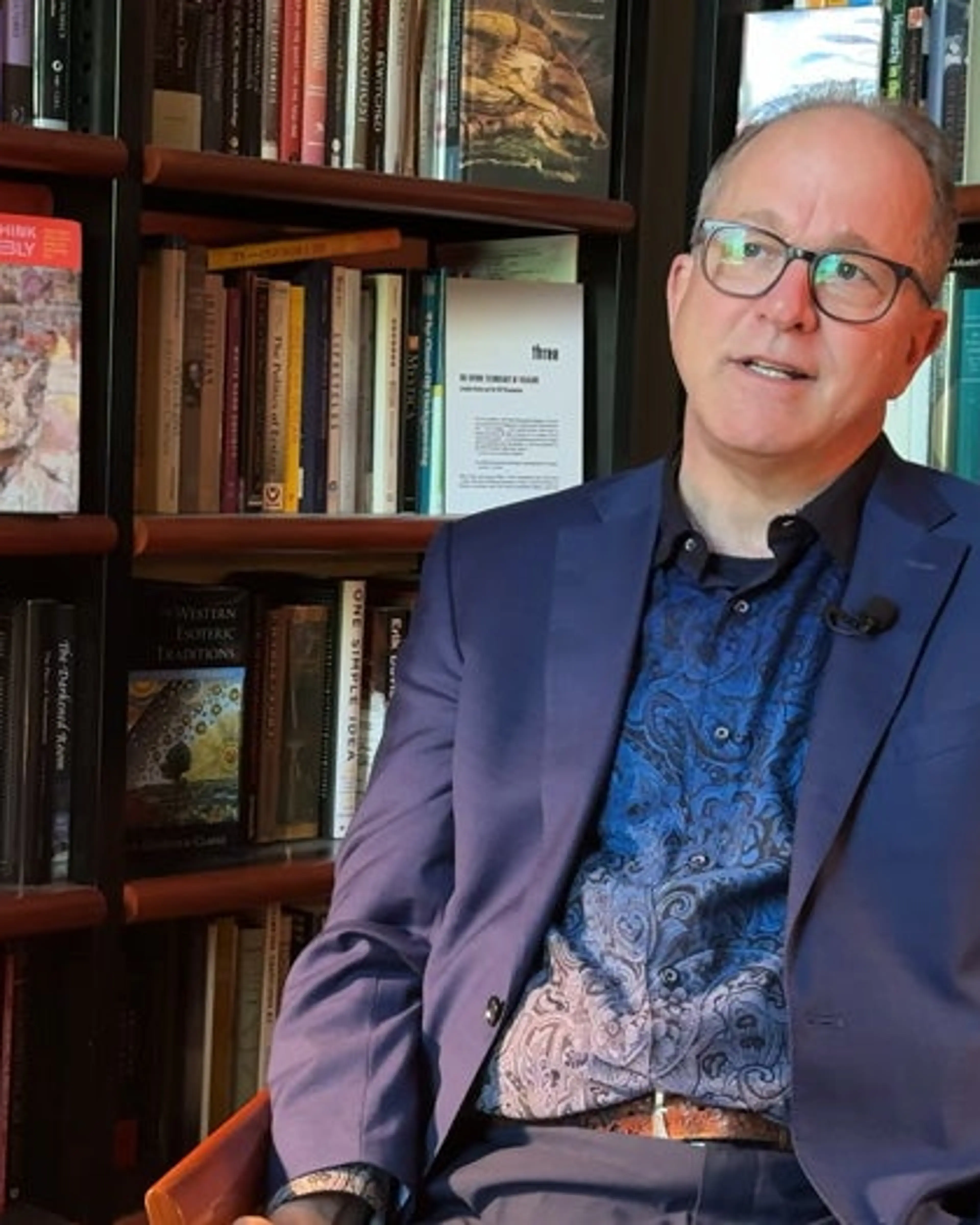 Archive X host Jeffrey J. Kripal sits in front of bookshelves.
