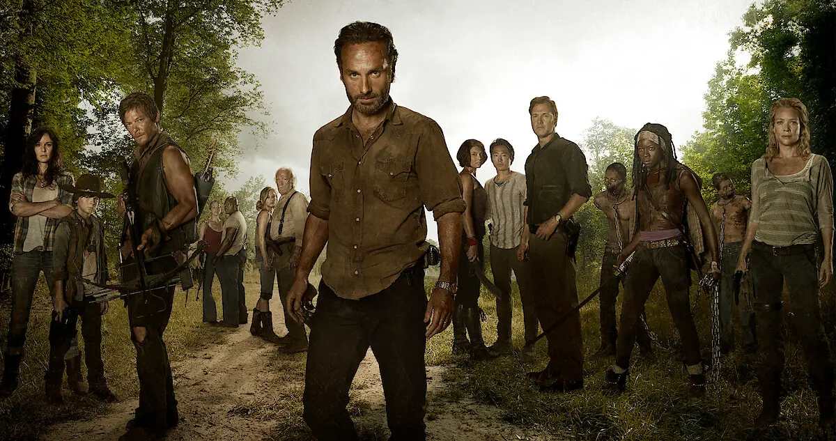 Rick Grimes stands in front of an ensemble of The Walking Dead survivors.