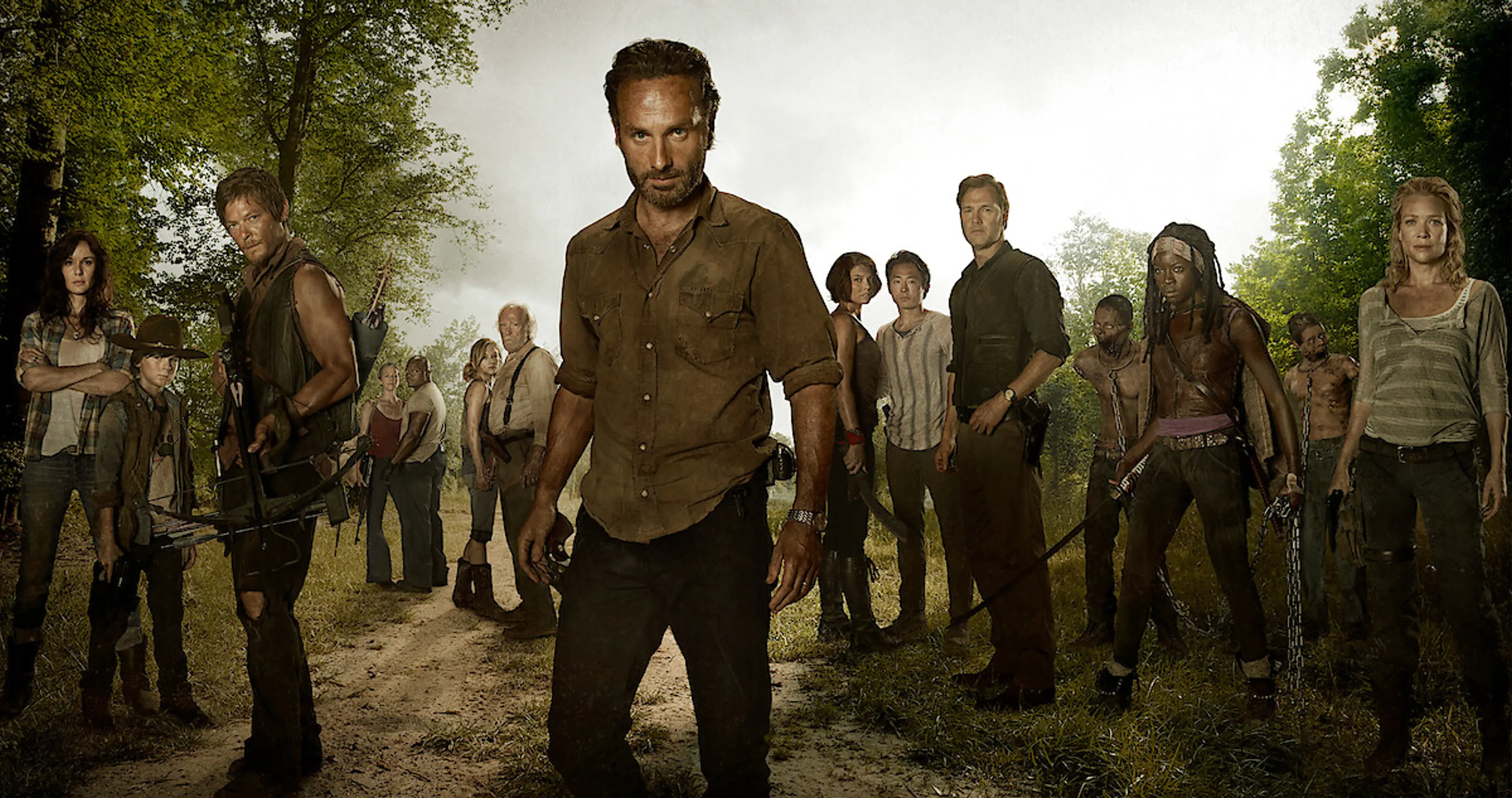 Rick Grimes stands in front of an ensemble of The Walking Dead survivors.