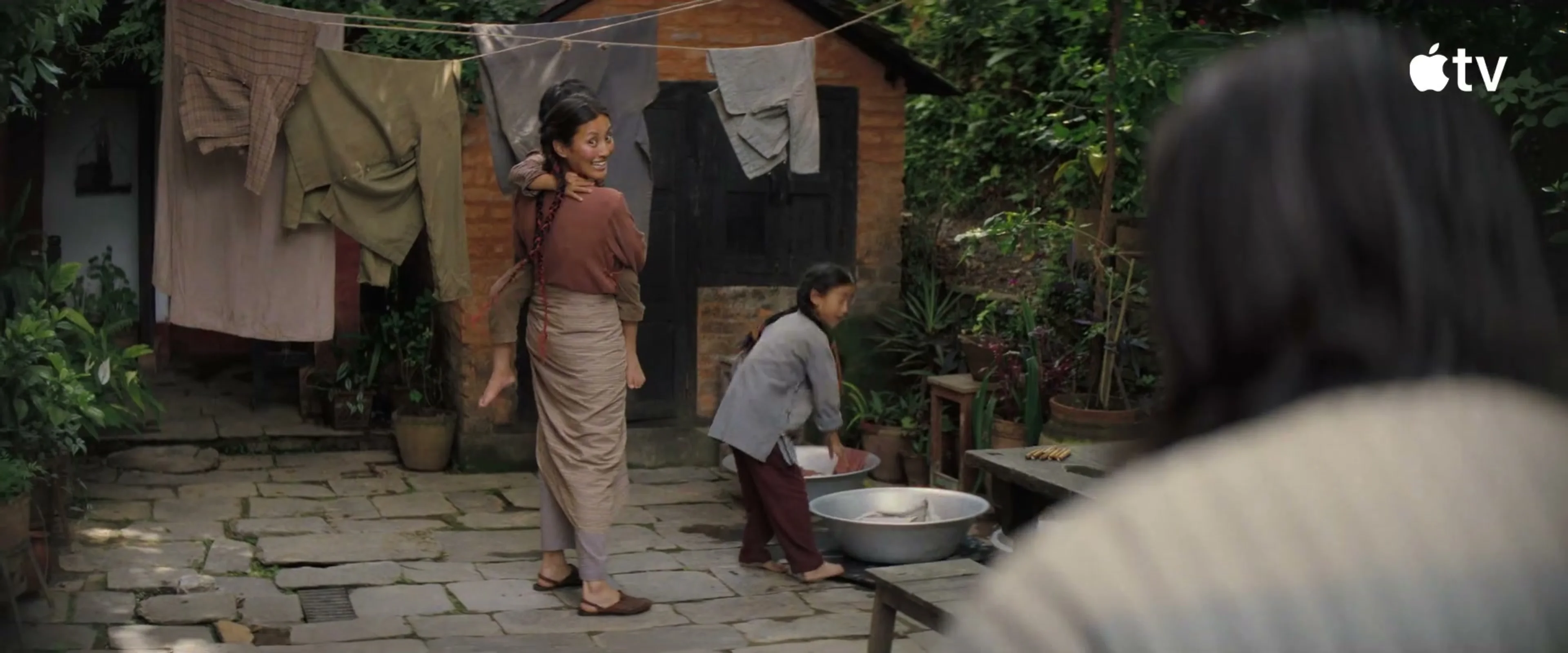 Dawa carries a child through the family courtyard in Tenzing.