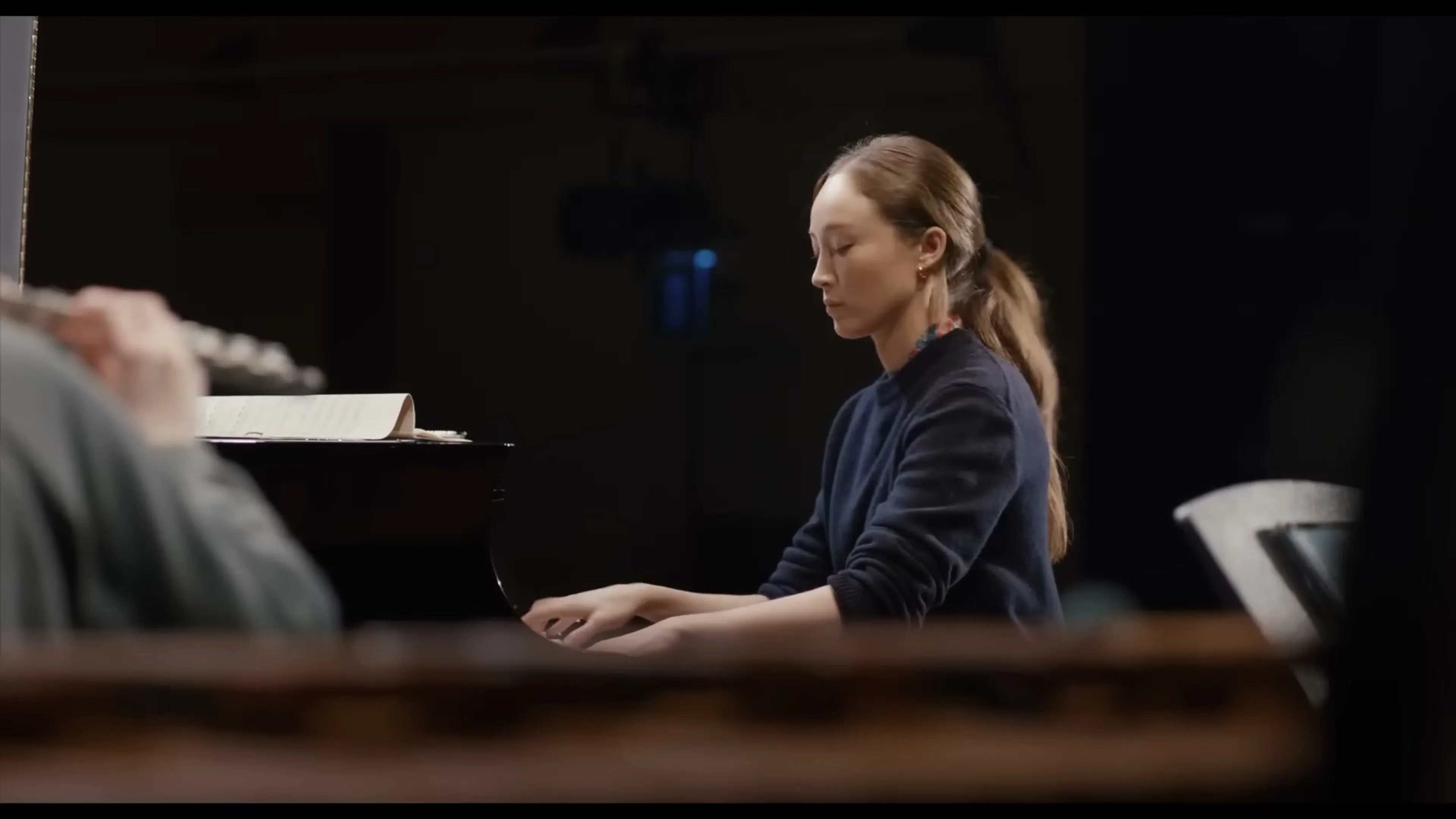 Ruthie plays a piano with sheet music in front of her.