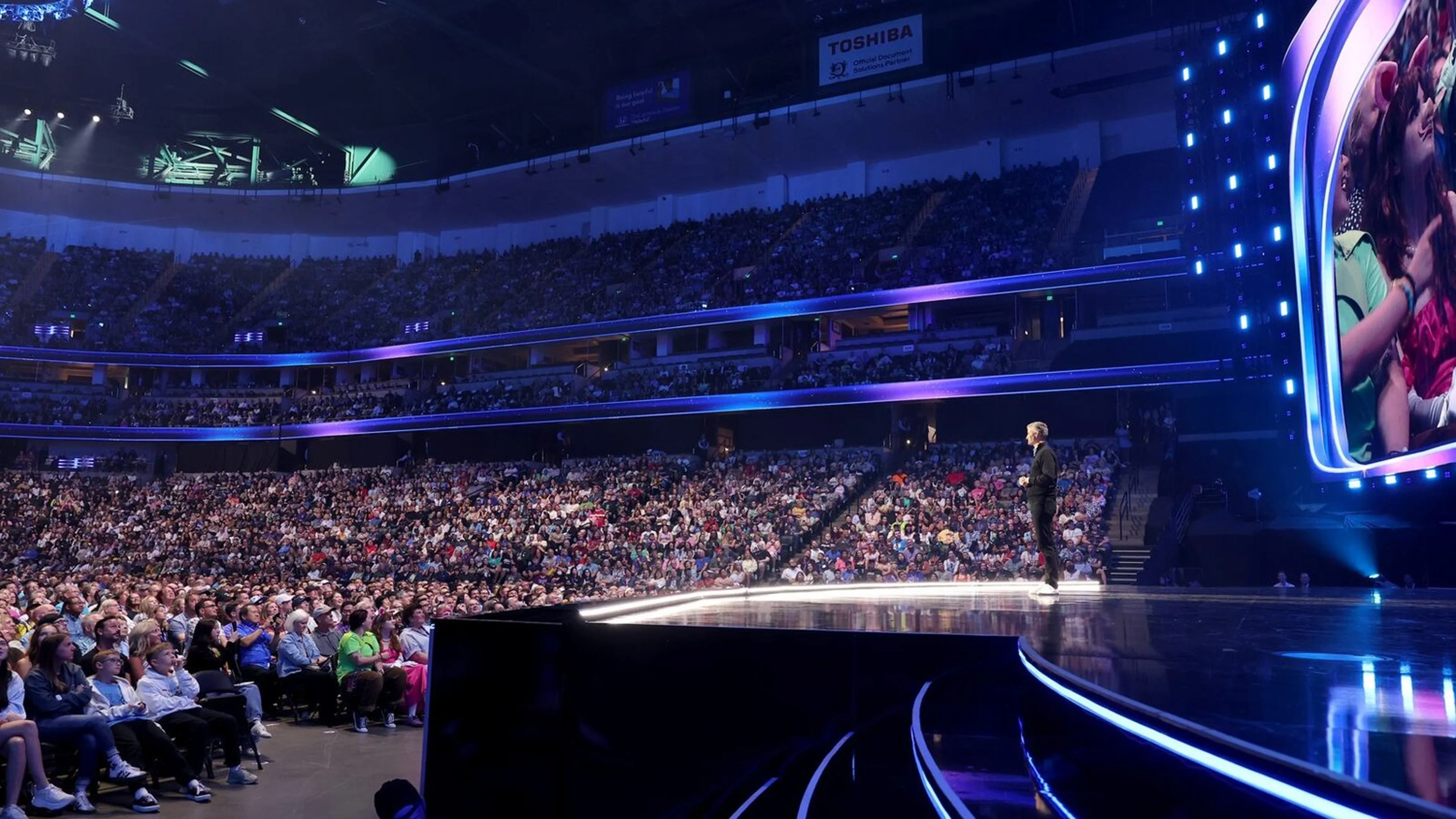 Josh D’Amaro stands onstage during Disney’s D23 entertainment showcase in front of a packed audience.
