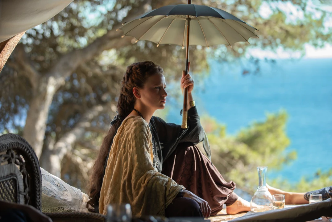 Elisabeth outdoors under a parasol in an official The Empress Season 3 image.