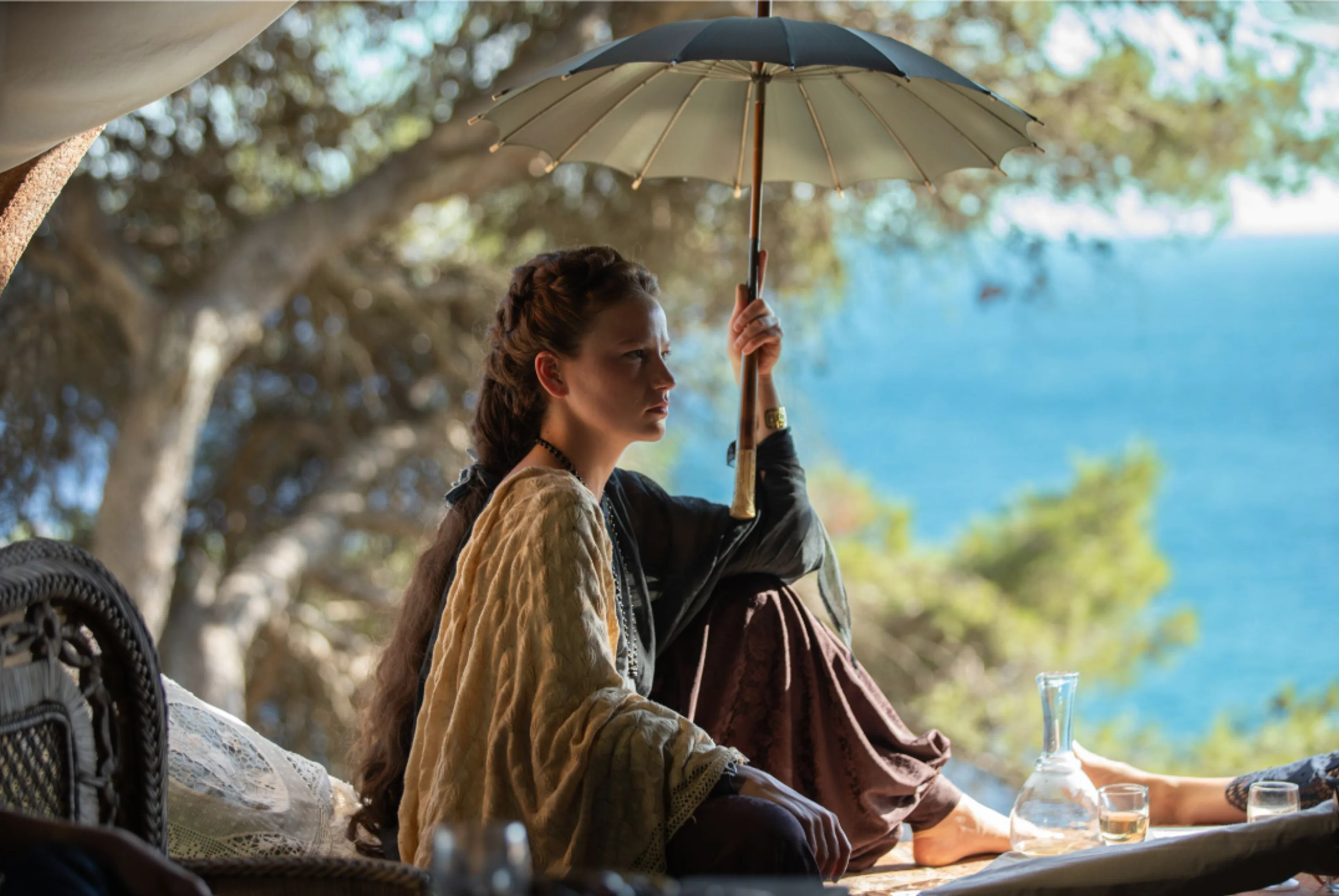 Elisabeth outdoors under a parasol in an official The Empress Season 3 image.