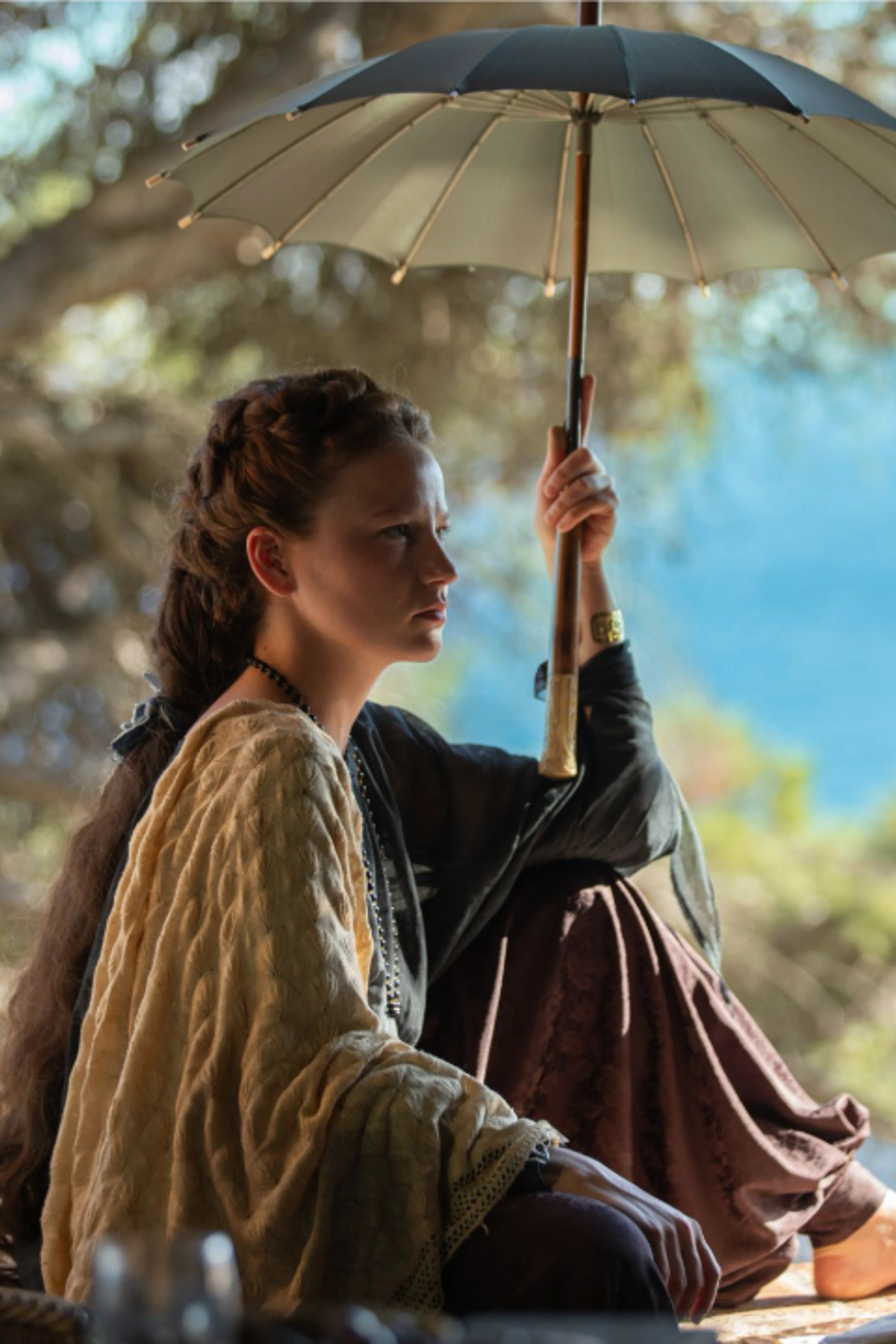 Elisabeth outdoors under a parasol in an official The Empress Season 3 image.