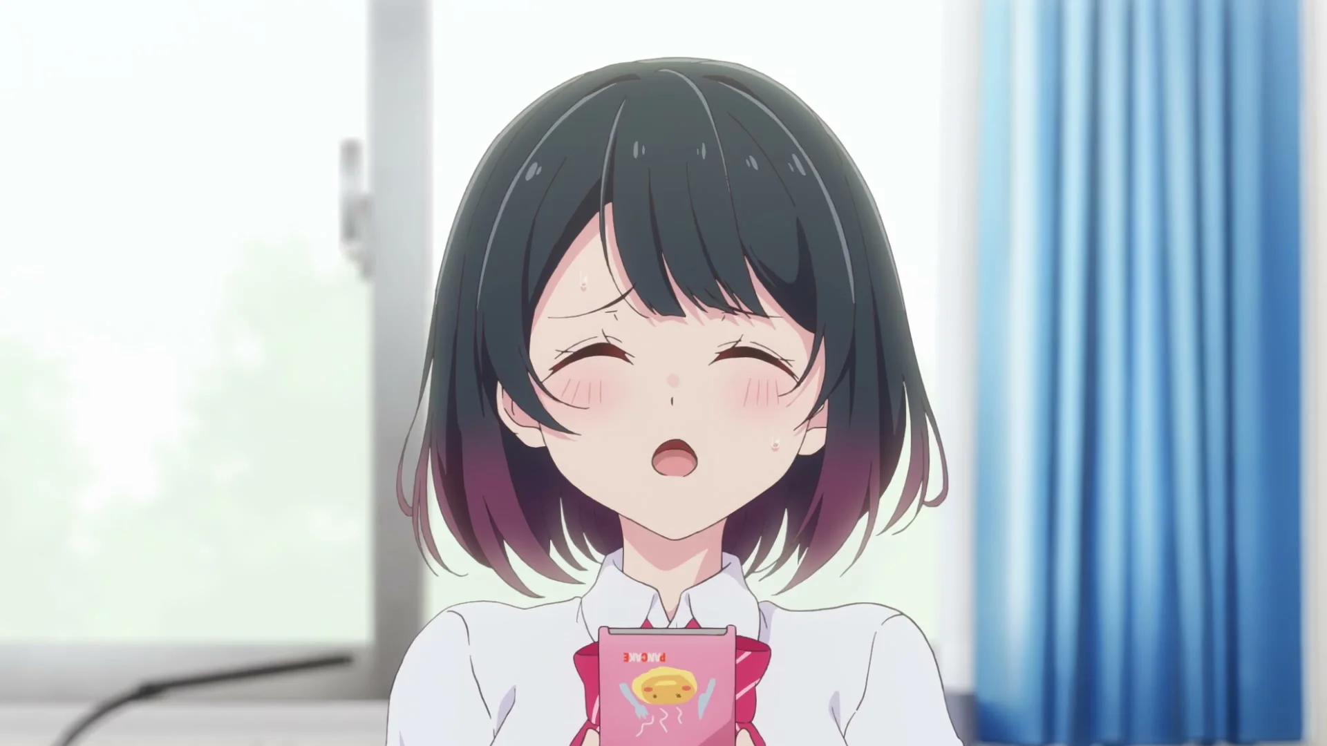 Koharu smiles with her eyes closed while holding a small snack package.