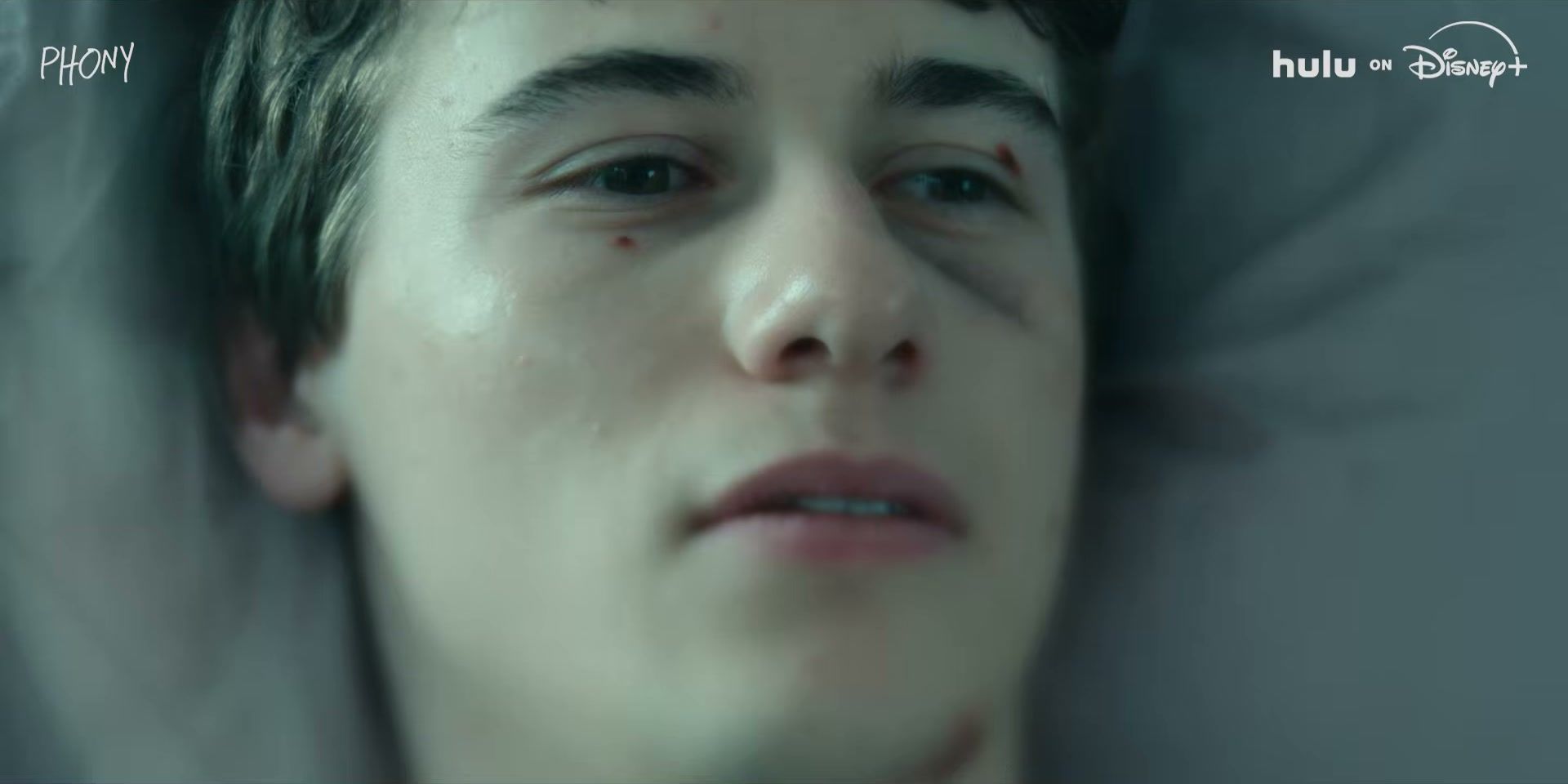 A teenager looks up in a close-up from the Phony trailer.
