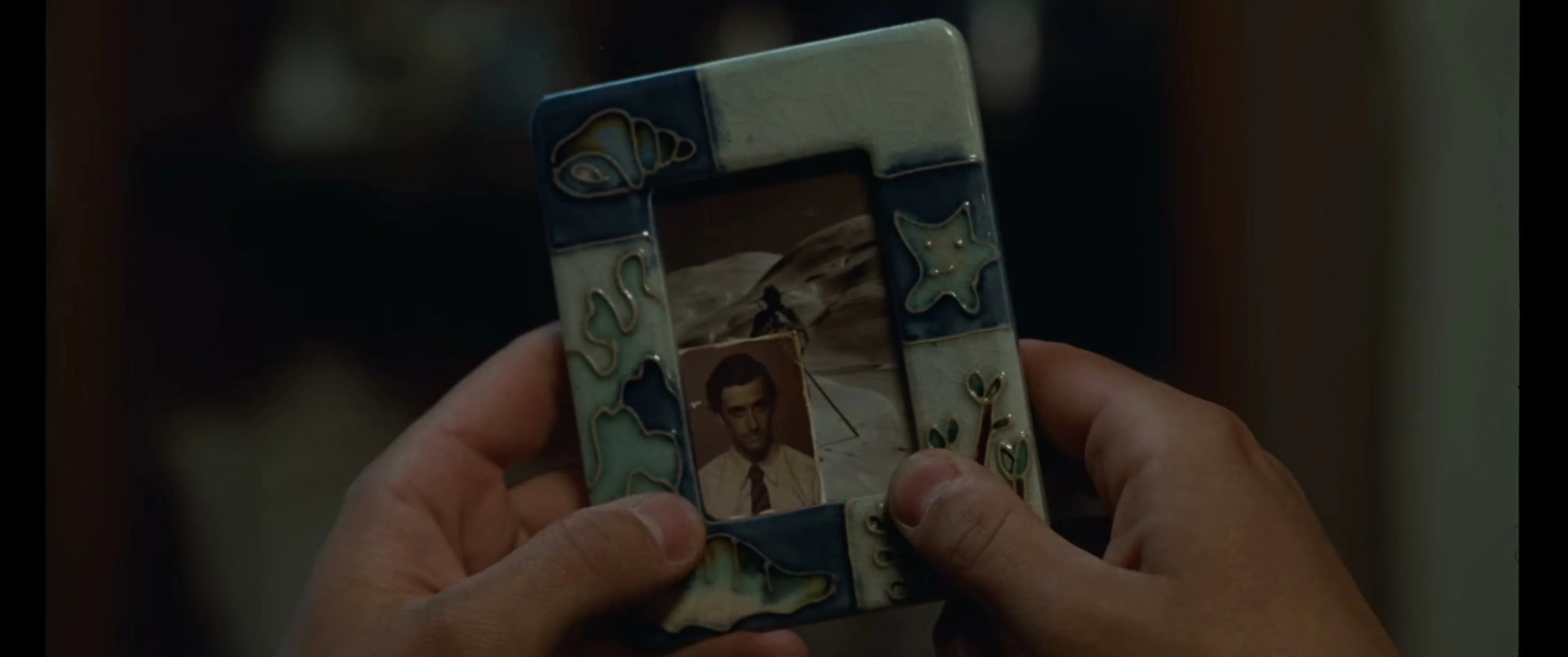A person holds a small photograph inside a decorated frame in La Bola Negra.
