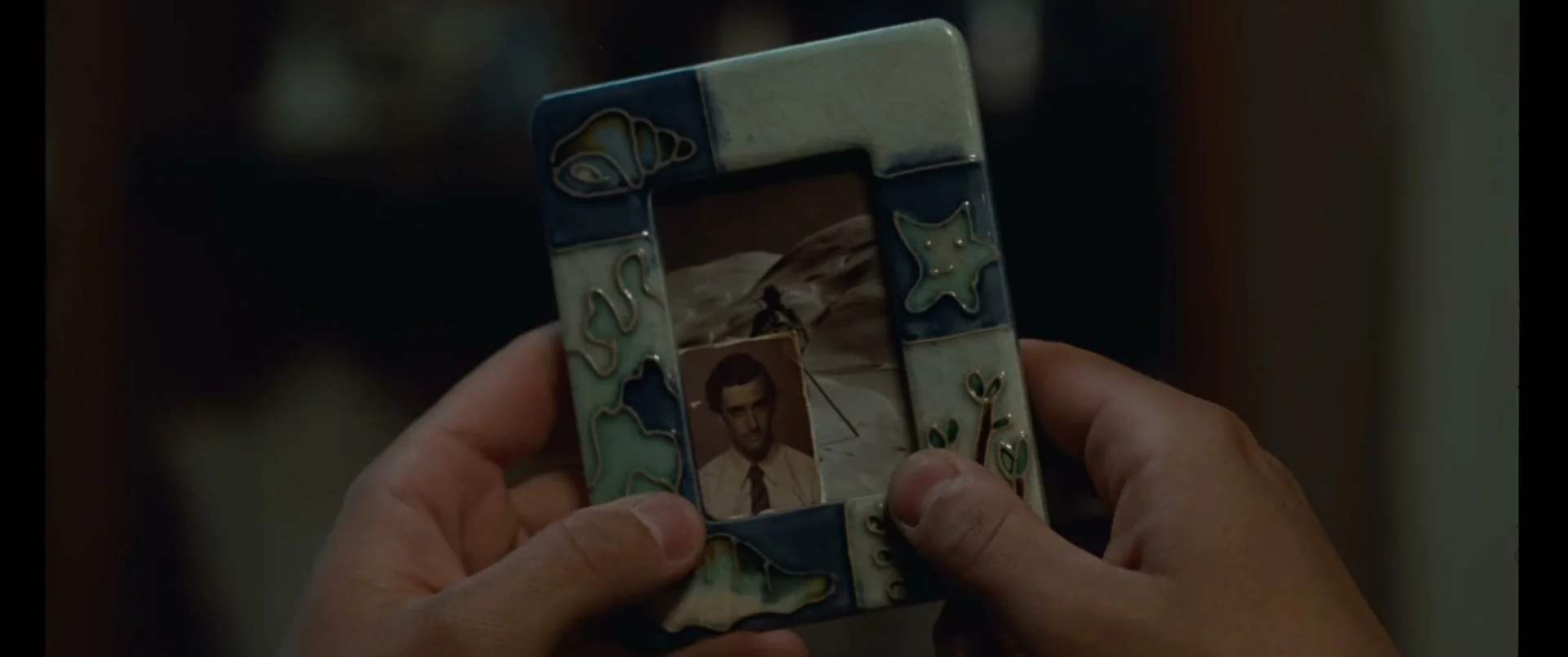 A person holds a small photograph inside a decorated frame in La Bola Negra.