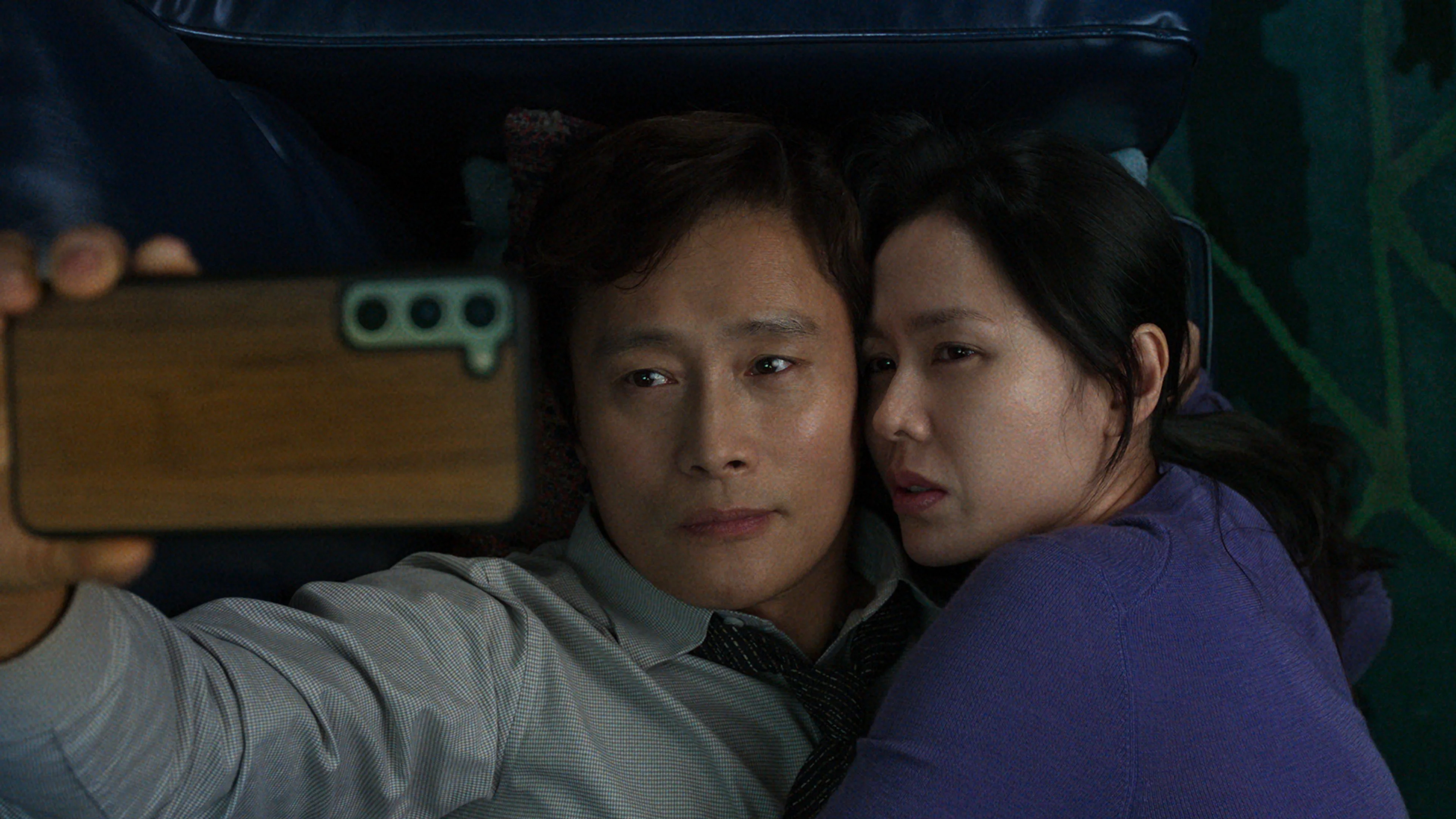 Man-su and Mi-ri lie close together while looking at a phone.