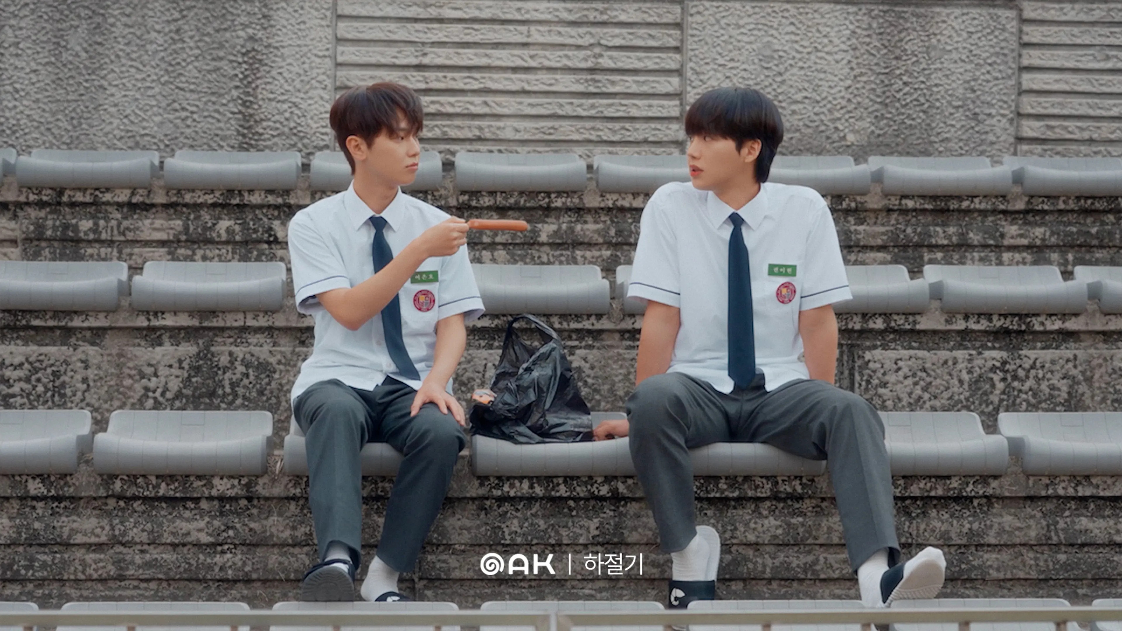 Two students sit and talk on outdoor steps.