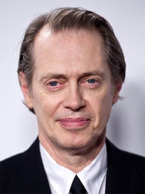 Portrait of Steve Buscemi wearing a dark suit and white shirt.