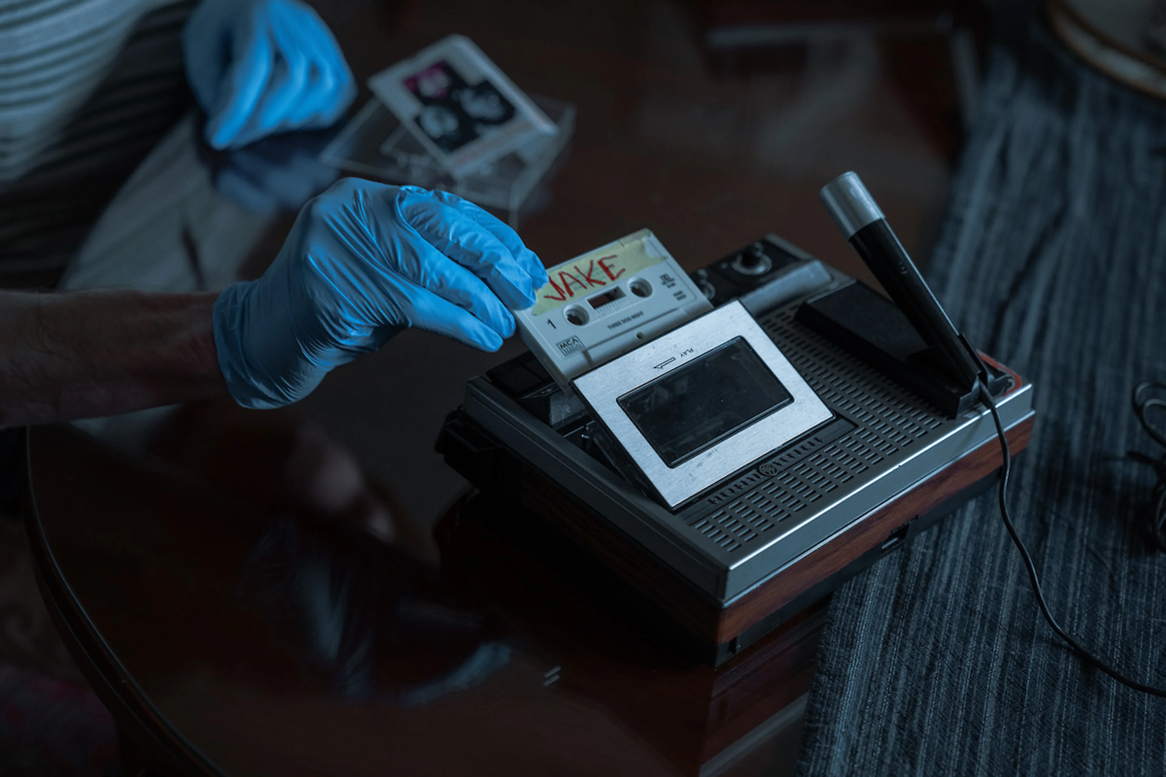 A gloved hand places a cassette into a tape recorder in The Whisper Man.