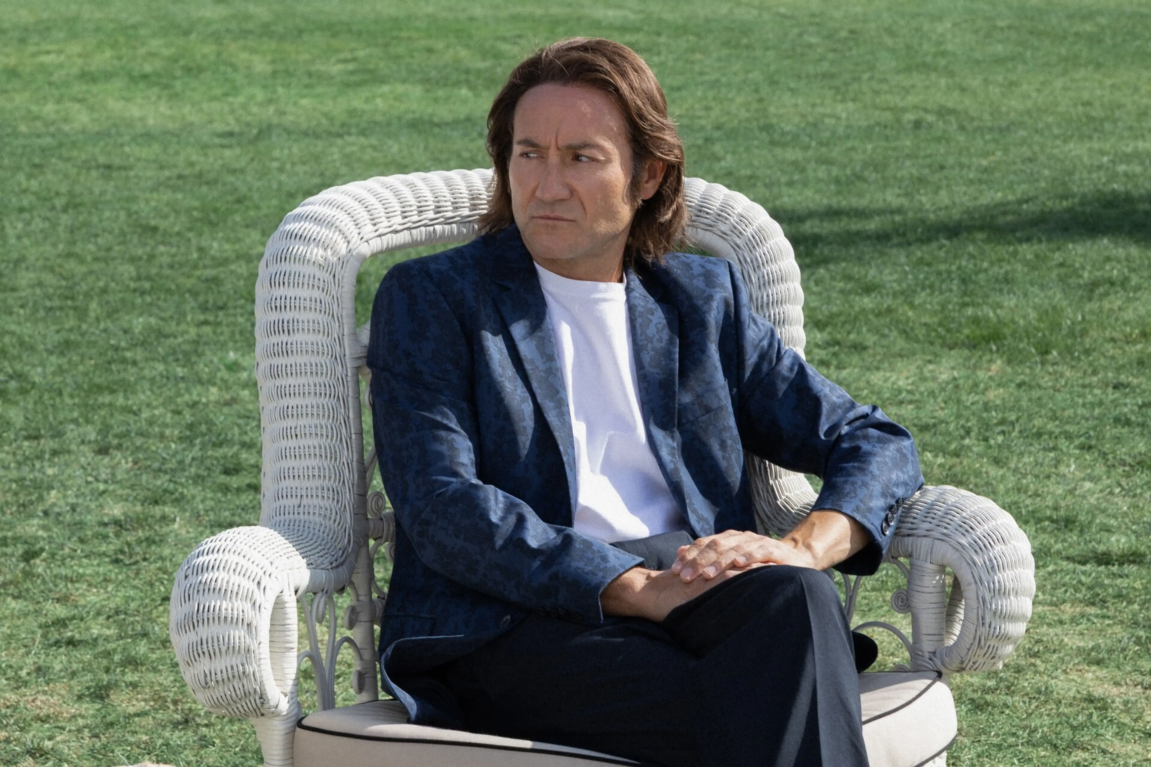 Carlos Santos as the mature Raphael sits outdoors in a blue jacket in A Day Like No Other.