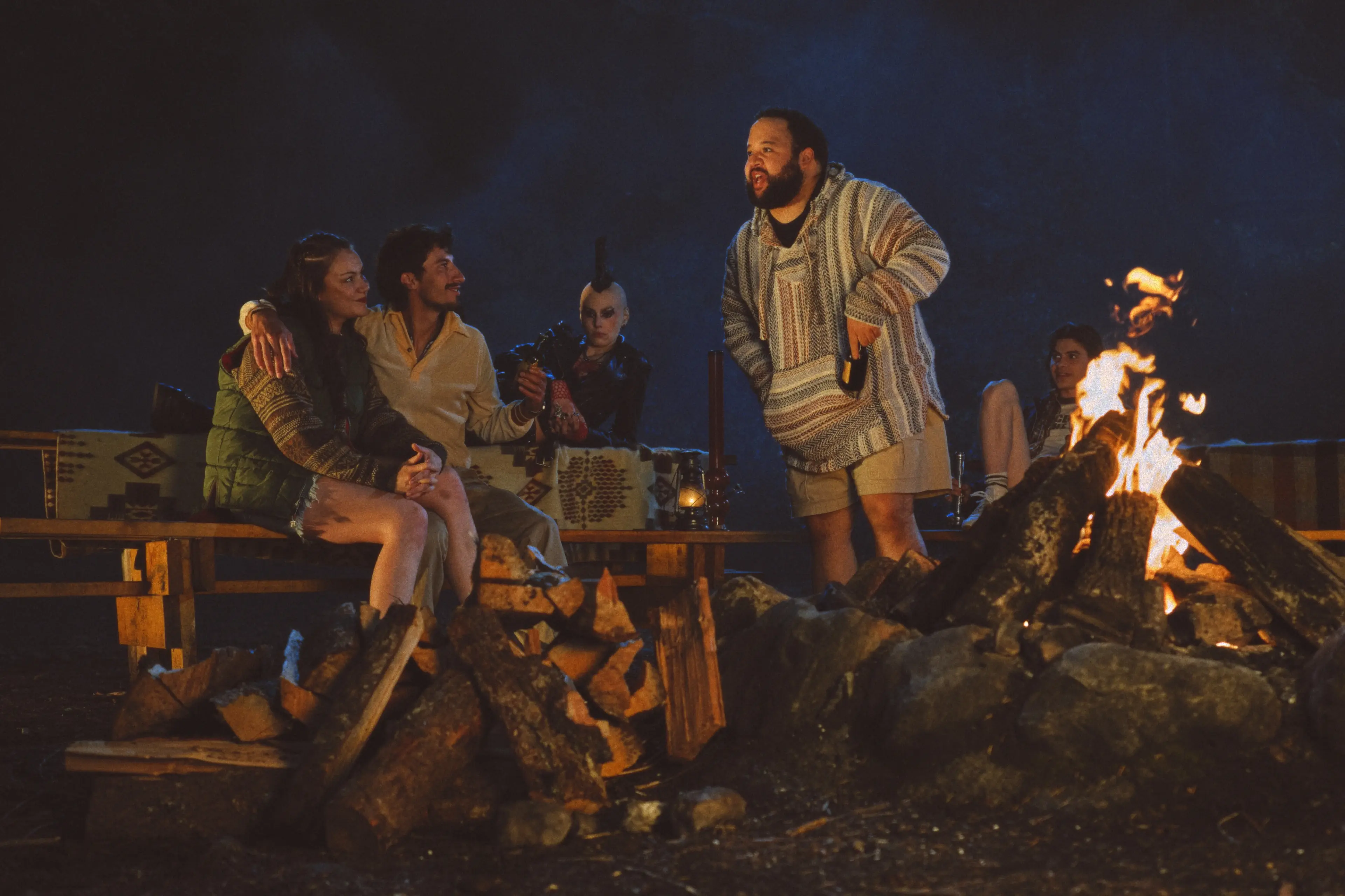 A group of camp counselors gather around a fire at night.