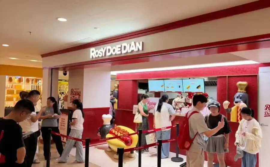 Rosy DoeDian hot dog counter at Nanjing’s Deji Plaza, with a red-and-white storefront and customers.