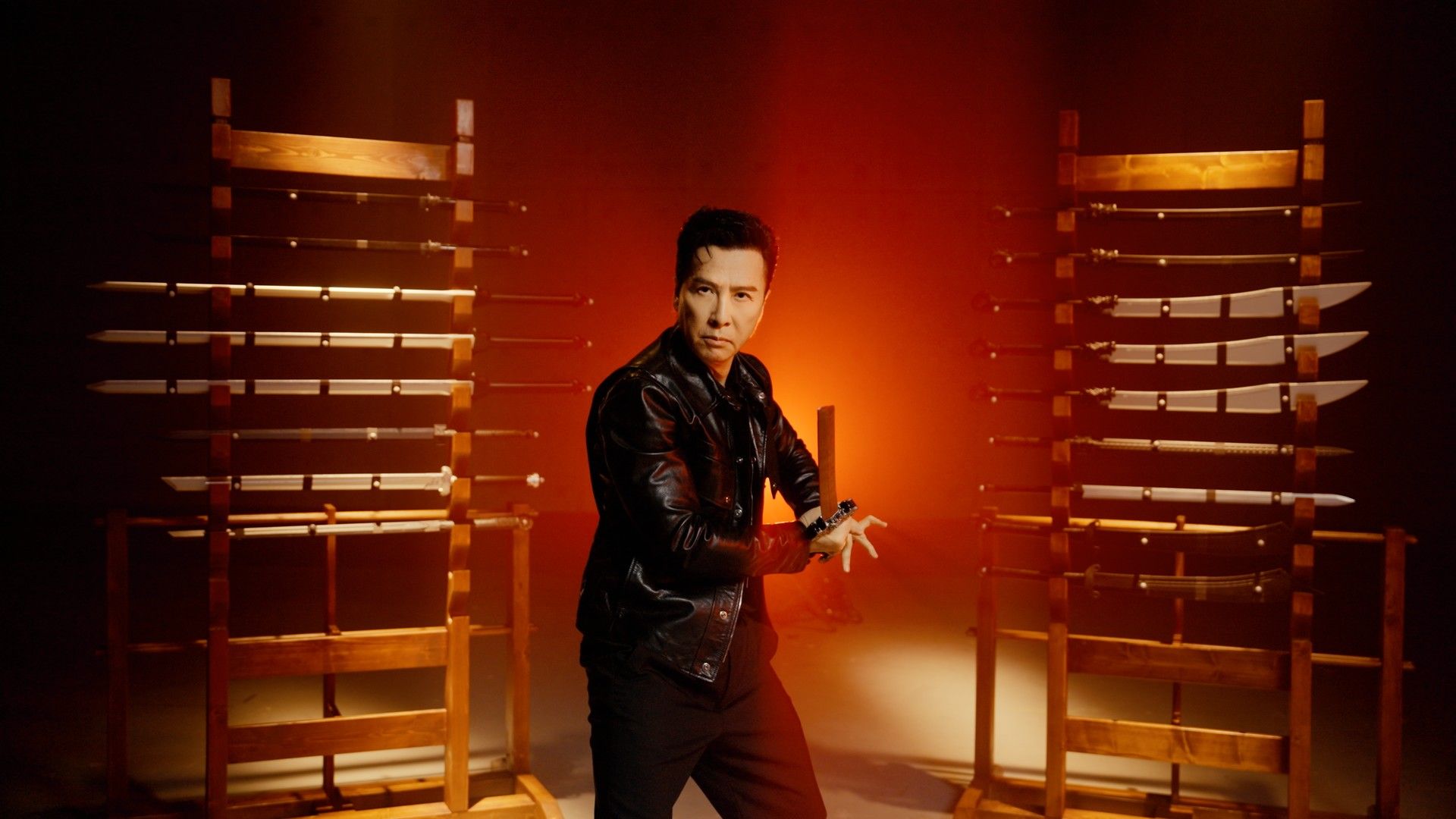 Donnie Yen poses with a sword between weapon racks while consulting on Phantom Blade Zero.