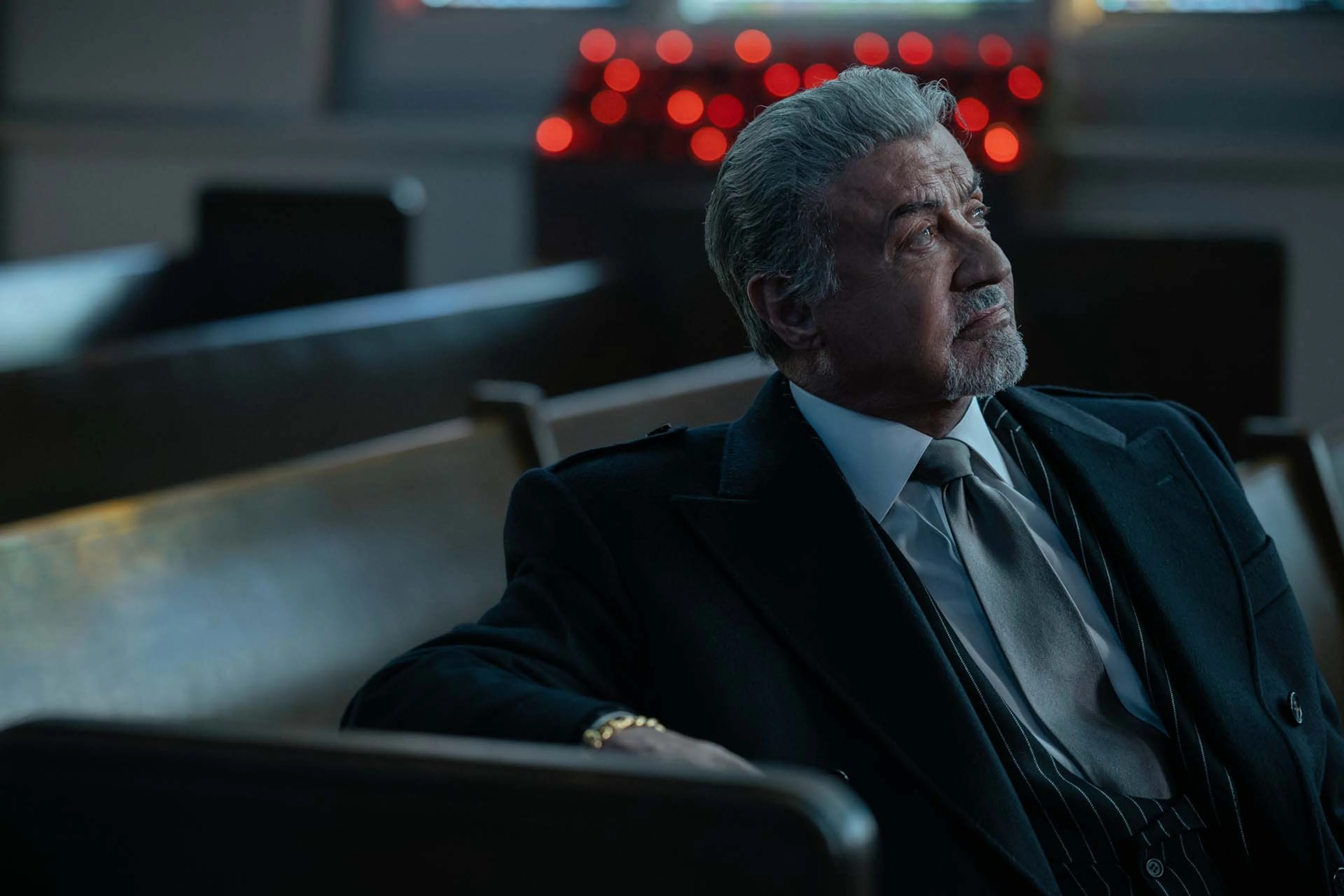 Sylvester Stallone as Dwight Manfredi looks upward while seated in a courtroom in Tulsa King Season 4.