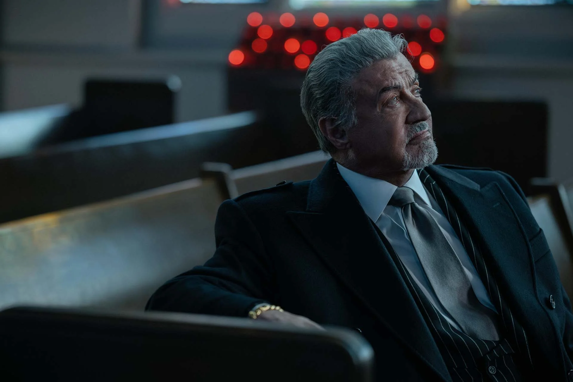 Sylvester Stallone as Dwight Manfredi looks upward while seated in a courtroom in Tulsa King Season 4.