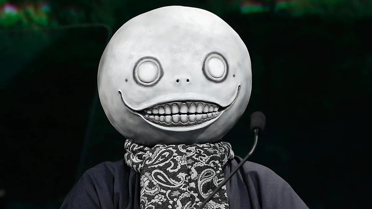 Yoko Taro stands centered while wearing his Emil mask at a gaming event.