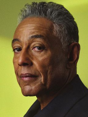 Portrait of Giancarlo Esposito in a dark shirt against a green background.