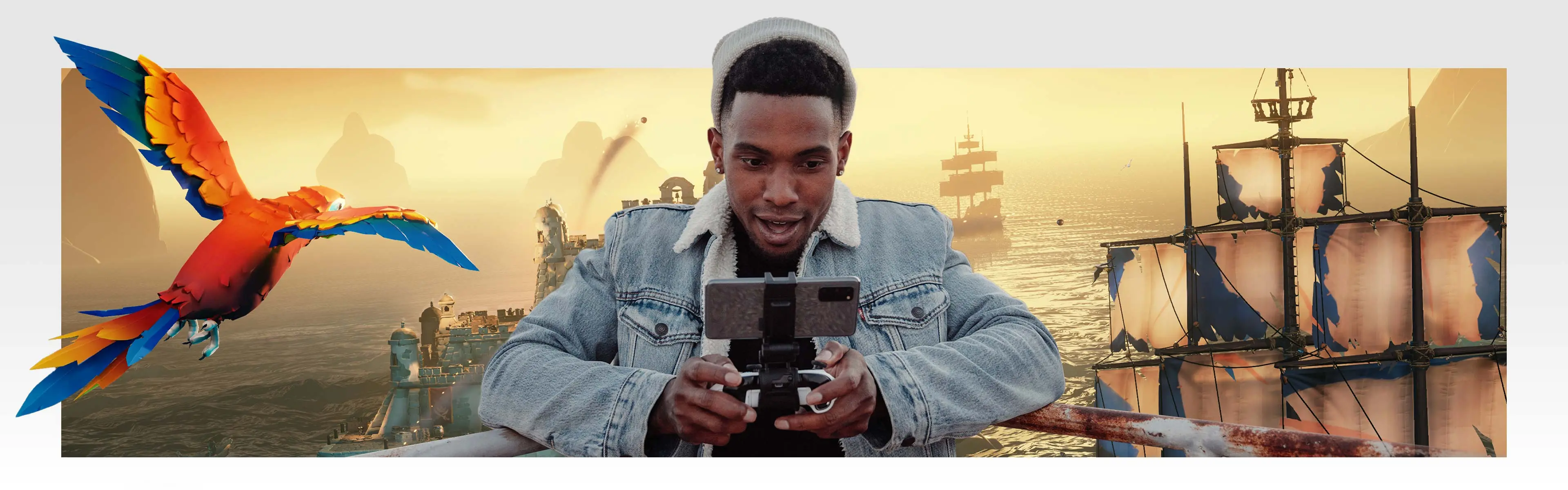 A player uses a phone mounted in a controller with Sea of Thieves behind him.