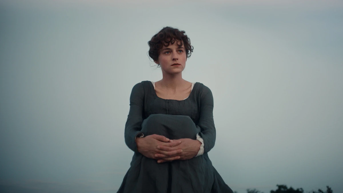 Emma Corrin sits outdoors in period costume as Elizabeth Bennet in Netflix’s Pride and Prejudice.