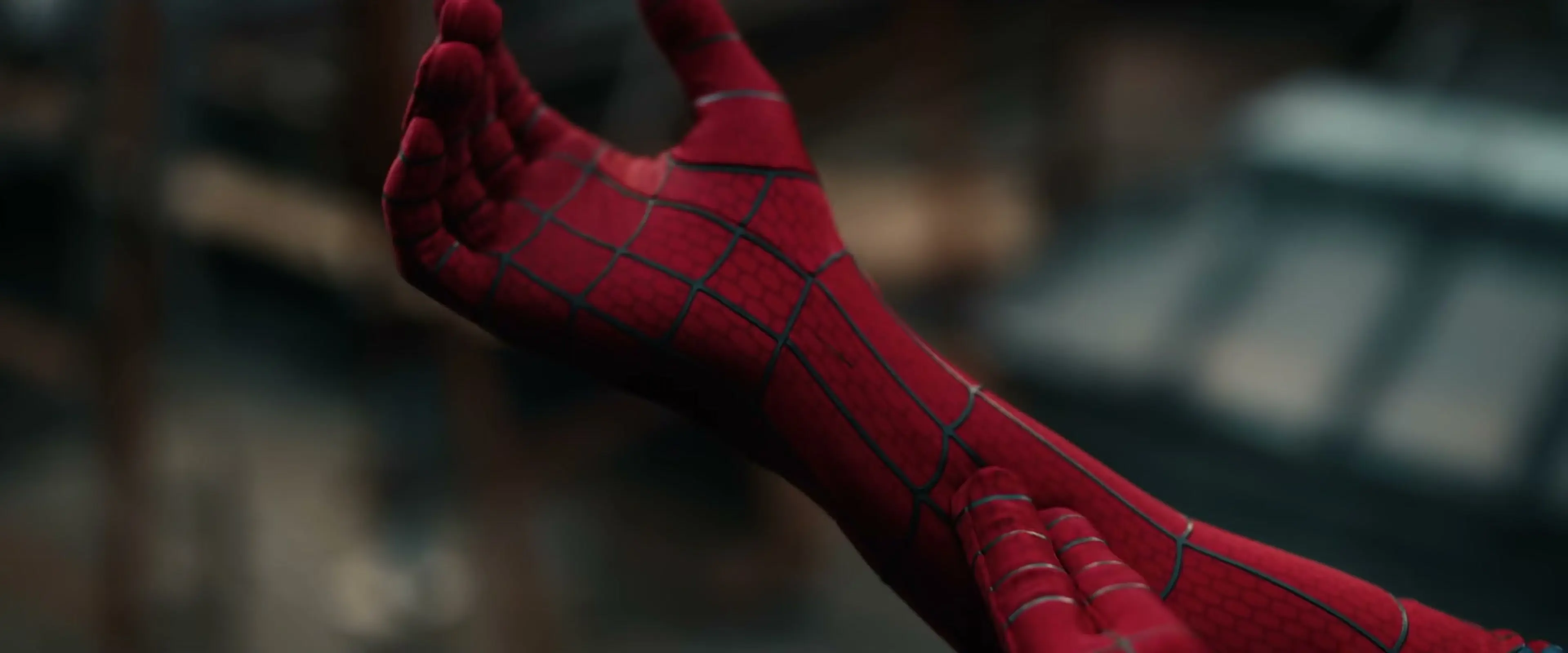 Close-up of Spider-Man’s red gloved hand and forearm held up in front of him.