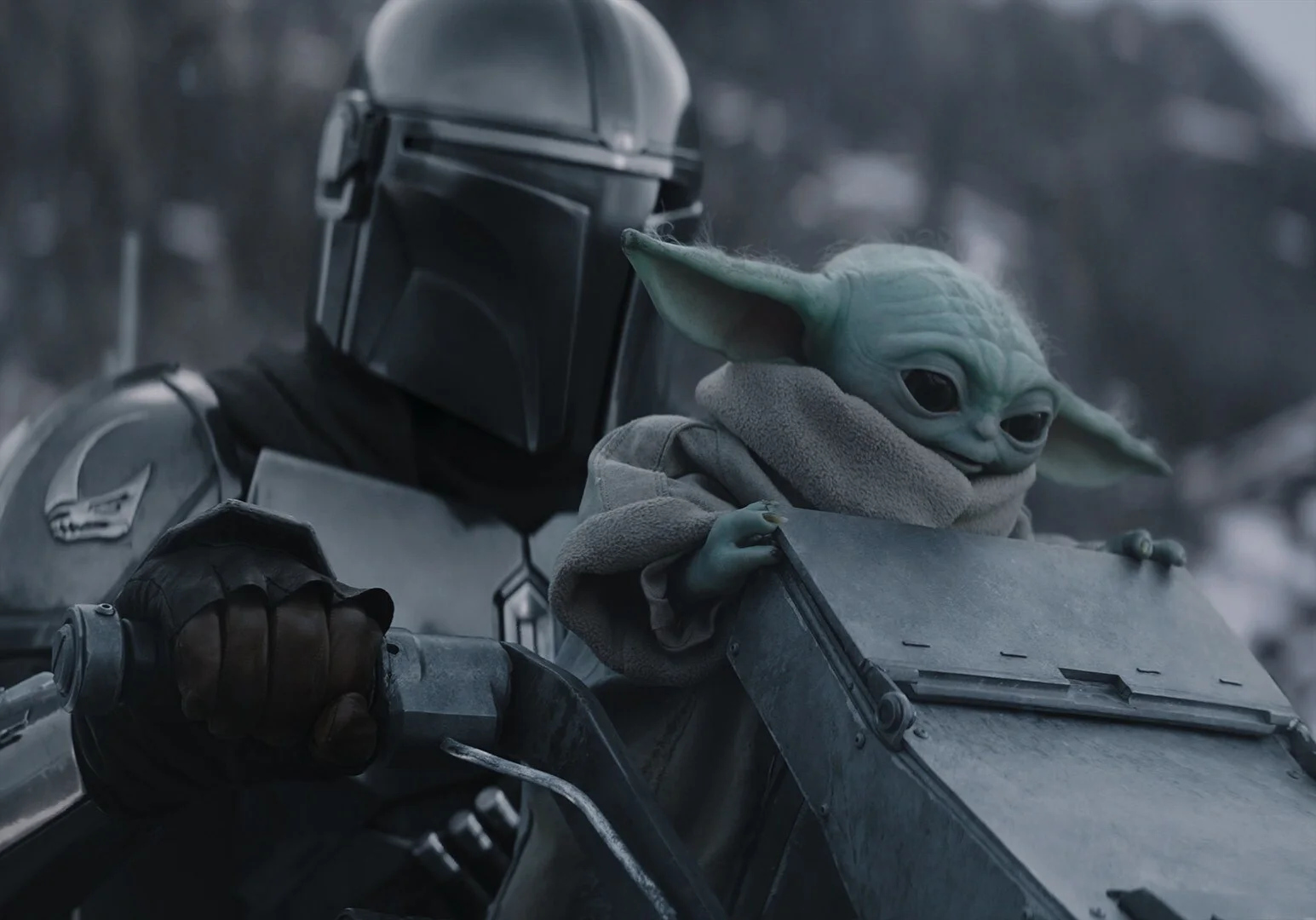 The Mandalorian carries Grogu in an official still from Star Wars: The Mandalorian and Grogu.