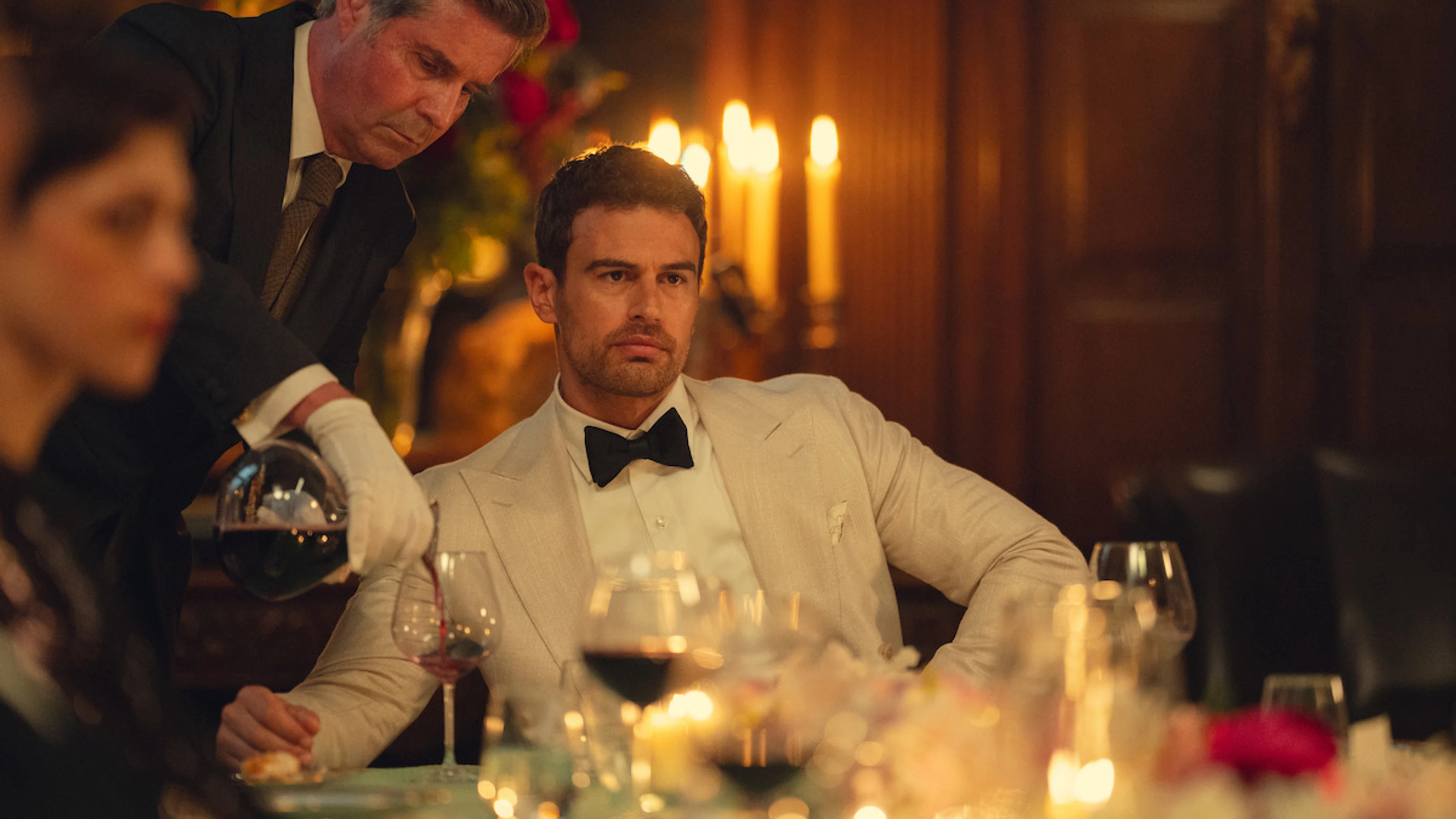 Theo James as Eddie Horniman sits at a candlelit dinner in The Gentlemen Season 2.